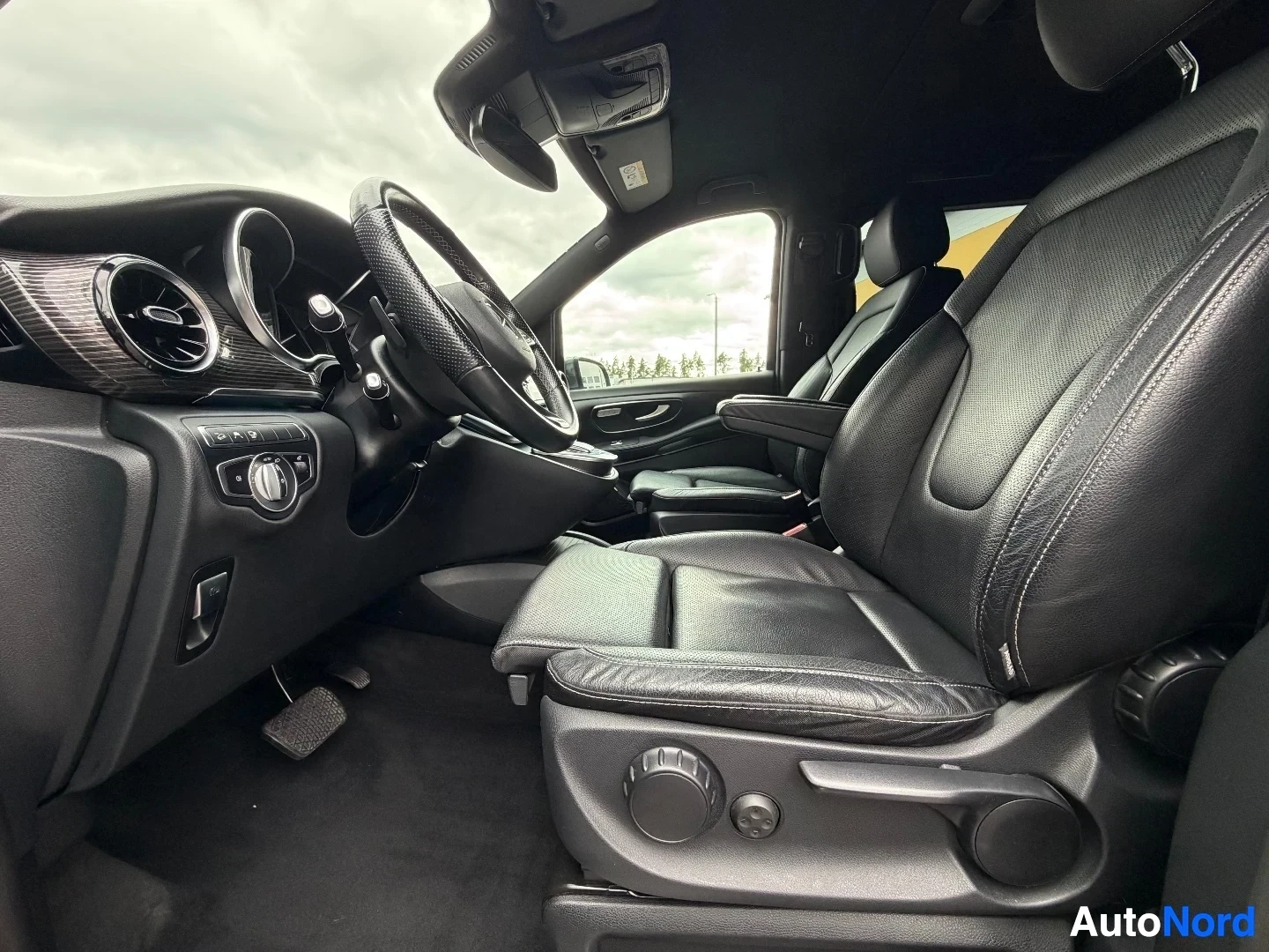 Driver's side cabin interior with steering wheel, seats, and dashboard controls