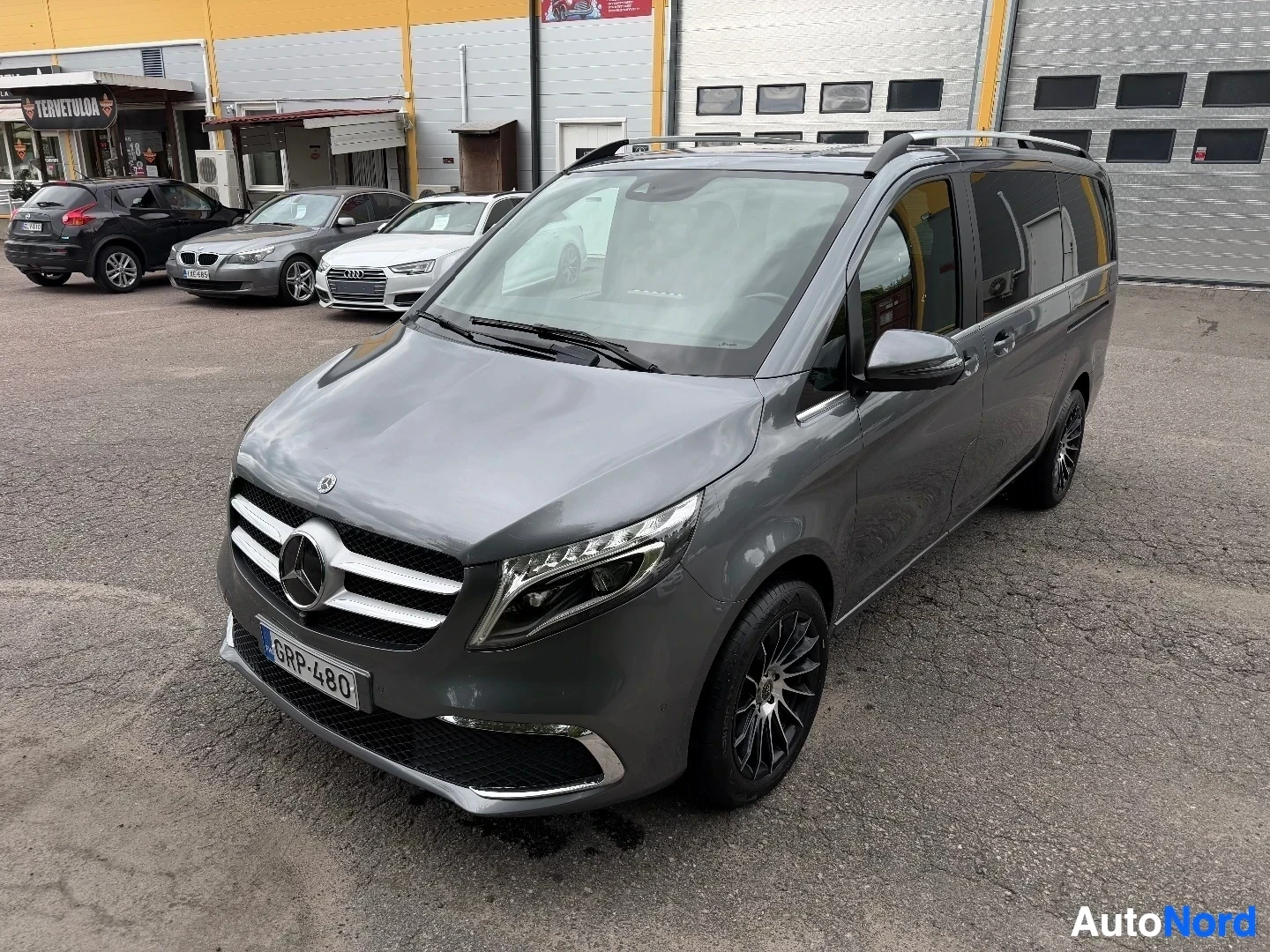 Gray Mercedes-Benz V-Class van front three-quarter angle with other vehicles visible