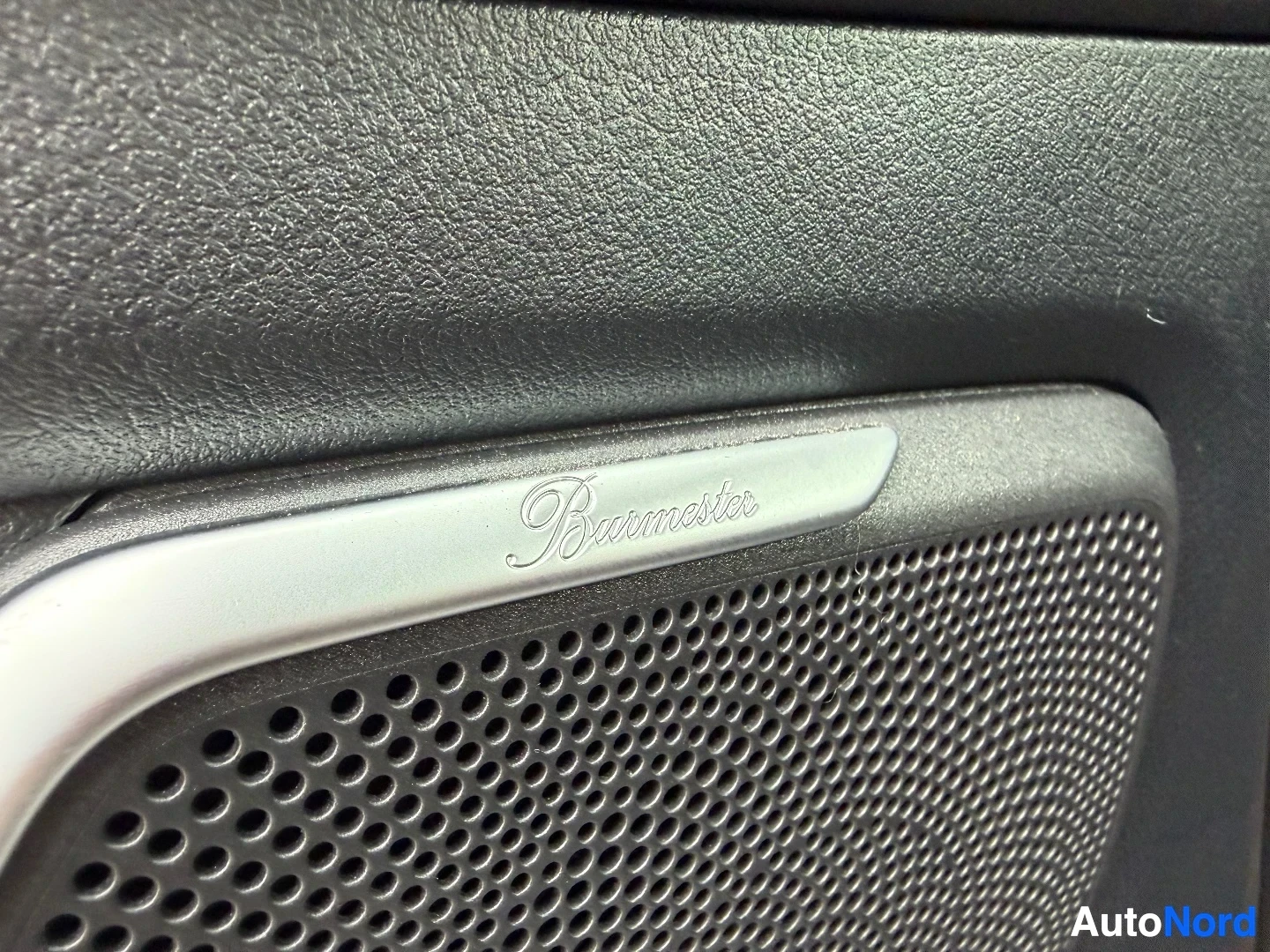 Interior detail showing Burmester speaker grille with textured door panel