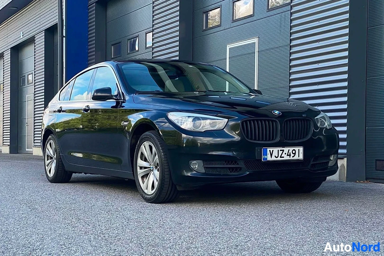 Etuviisto, nokka oikealle: Tummansininen BMW Gran Turismo sedan kuvattu edestä hieman vasemmalta, näkyvät etuosa ja vasen sivu, rekisterikilvessä