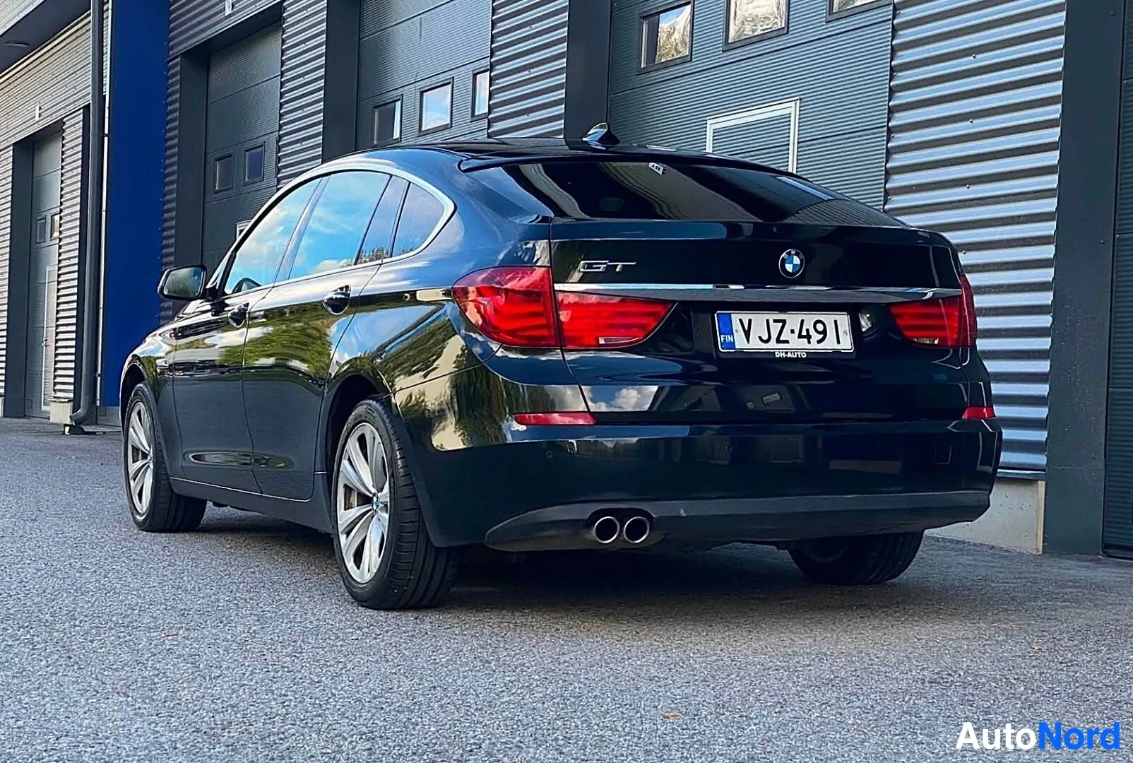 Takaviisto: Tummansininen BMW sedan kuvattu takaa ja vasemmalta puolelta, näkyvät takaa ja vasen sivu, rekisterikilvessä, tekstissä GT ja BM AUTO