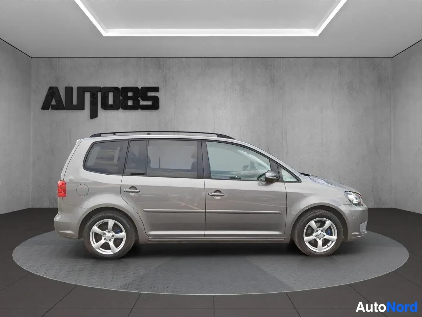 Sivulta: Hopea Volkswagen Touran sivukuvassa oikealle suuntautunut, neliovinen monipaikkainen ajoneuvo, rekisterinumero ei näkyvä tässä kulmassa.