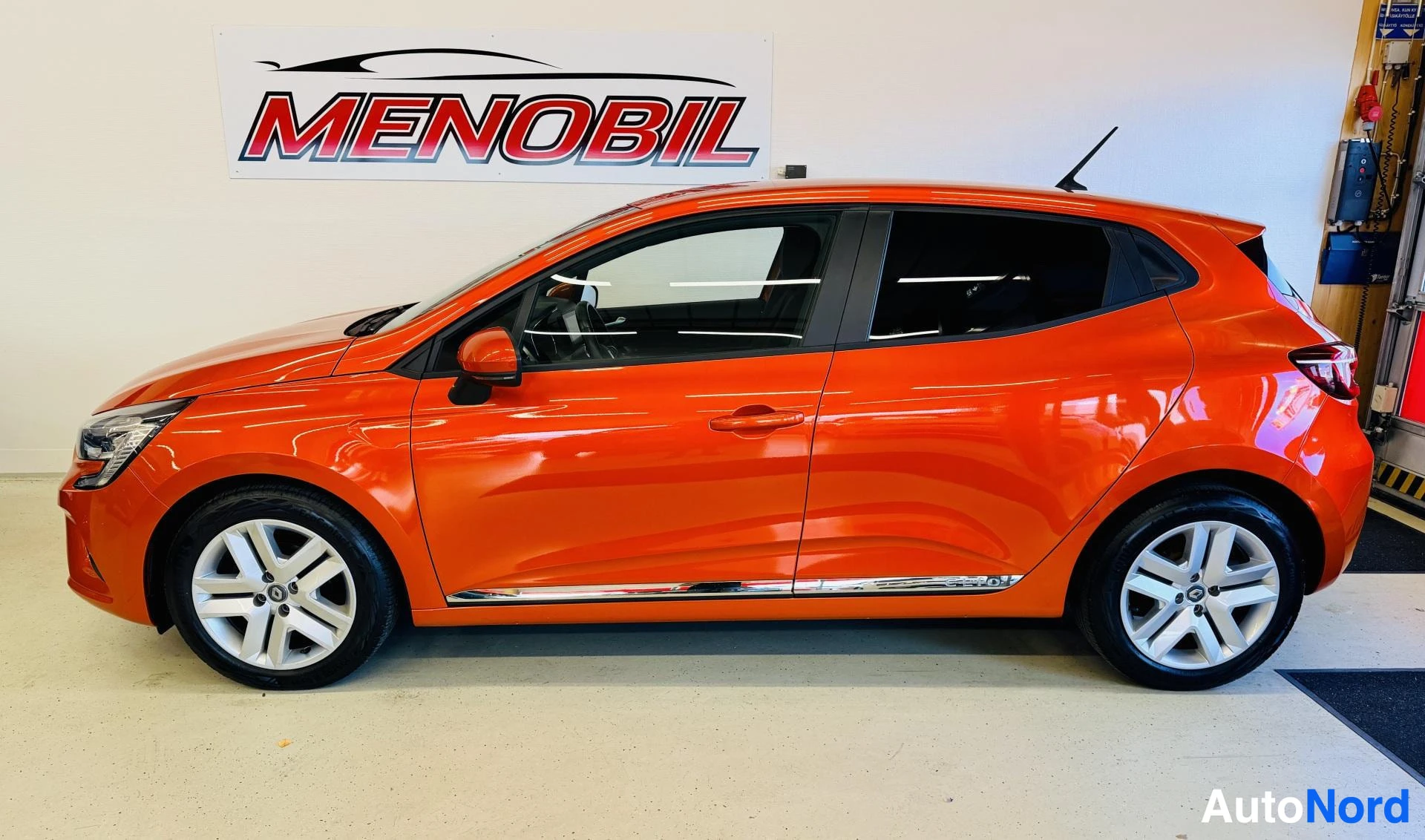Sivulta: Oranssi Renault Clio, sivu näkymä oikealle, Menobil autoliikkeen hallissa
