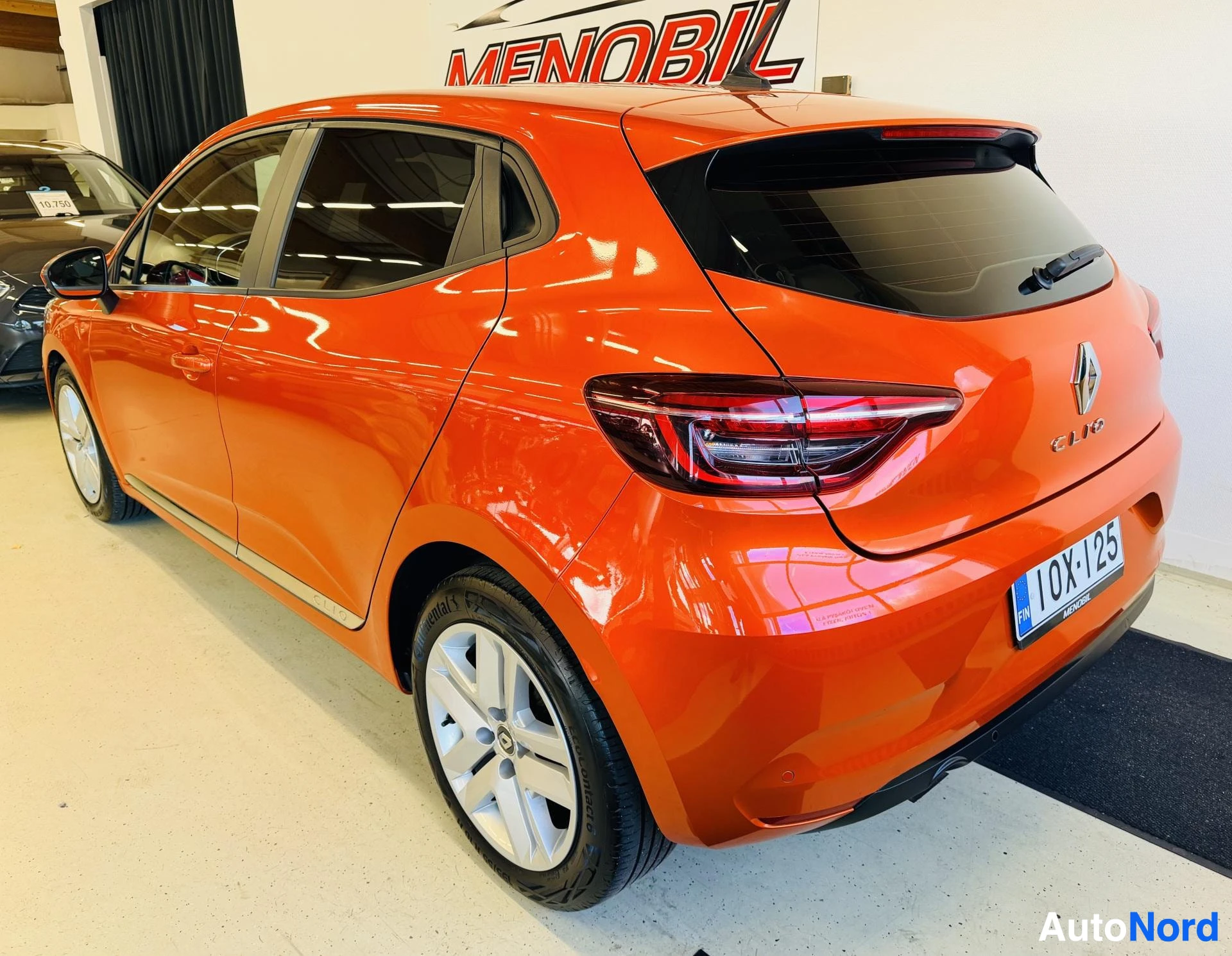 Takaviisto: Oranssi Renault Clio, takapuoli kolmelle neljäsosalle käännettynä vasemmalle, Menobil autoliikkeen hallissa