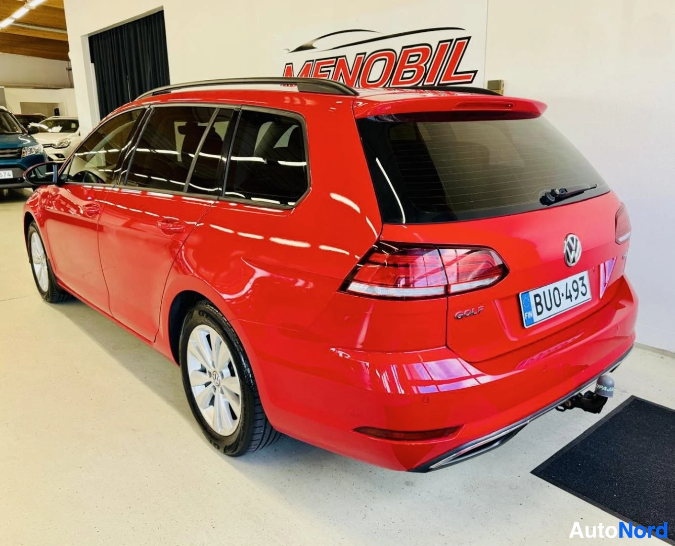 Takaviisto: Punainen Volkswagen Golf Variant, takaosa kolmelta neljännekseltä, sisähallissa, rekisteritunnus, valkokantiset pyörät, Golf-merkintä takaa näkyvissä
