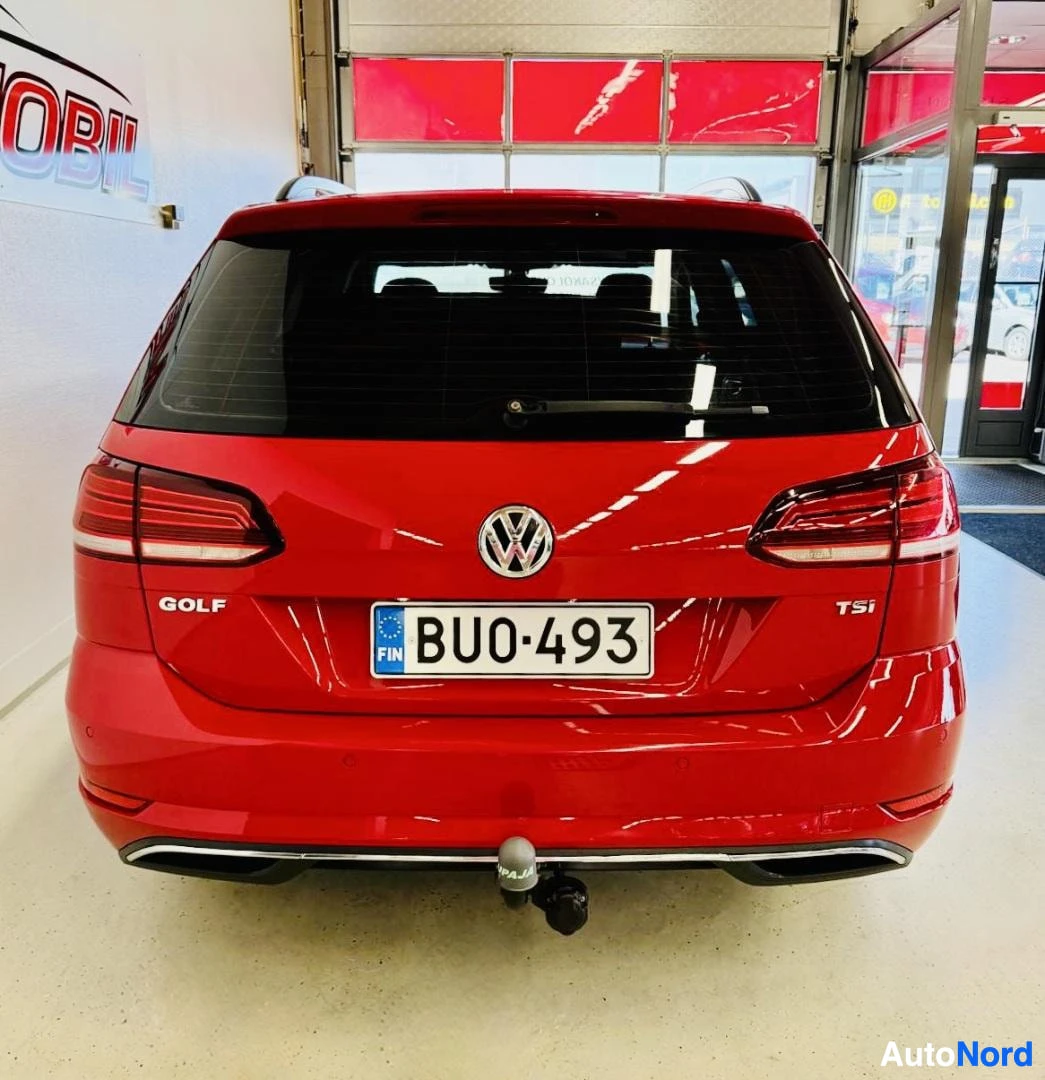 Takaa: Punainen Volkswagen Golf, takanäkymä. Rekisterinumero näkyy keskellä. 'GOLF' ja 'TSi' merkinnät näkyvissä takapaneelissa. Harmaa hinauskoukku alapuolell