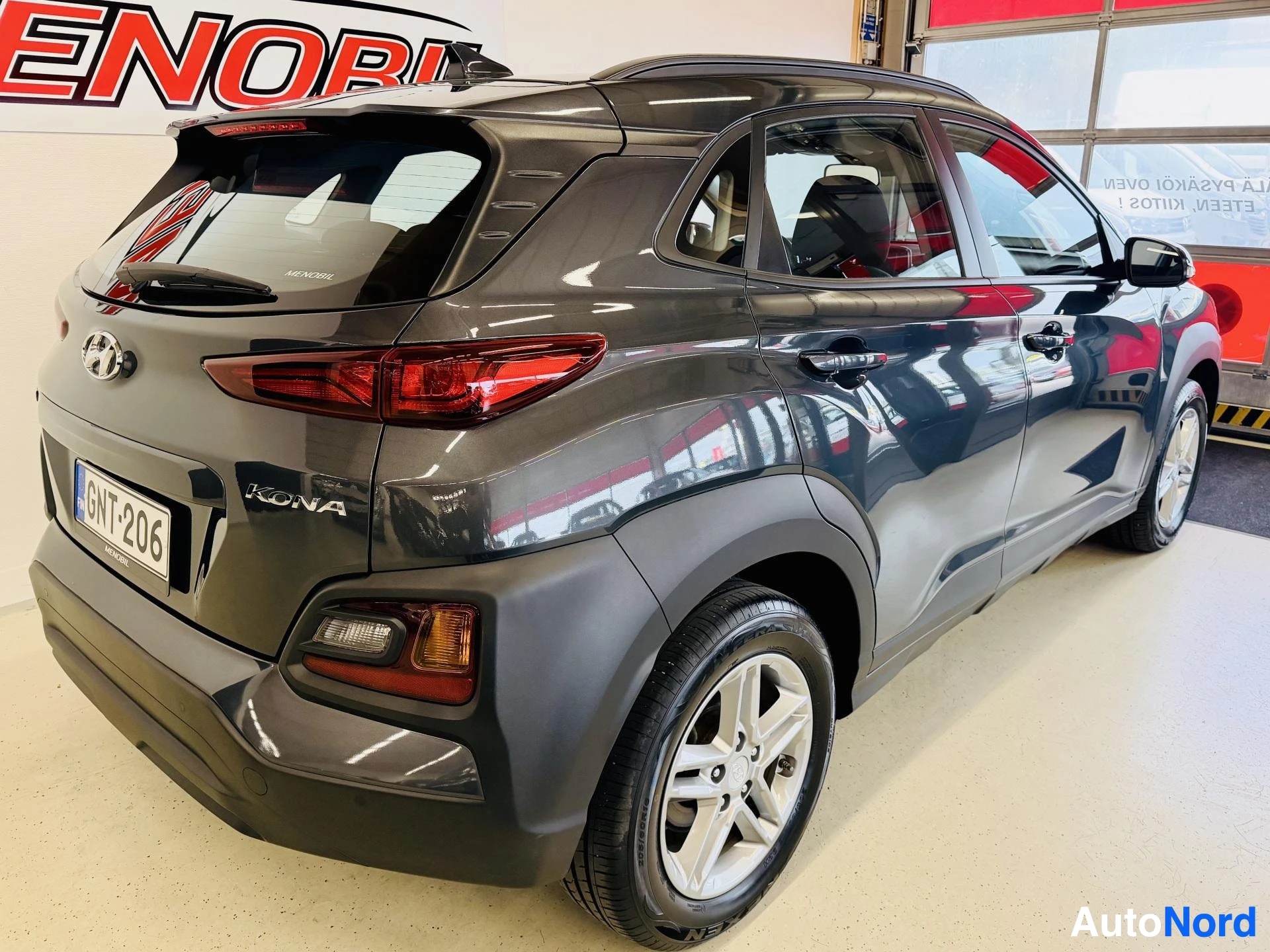 Takaviisto: Harmaa Hyundai Kona seisoo näyttelyhallissa, kuvattu takaa-sivulta. Rekisterikilvessä lukee