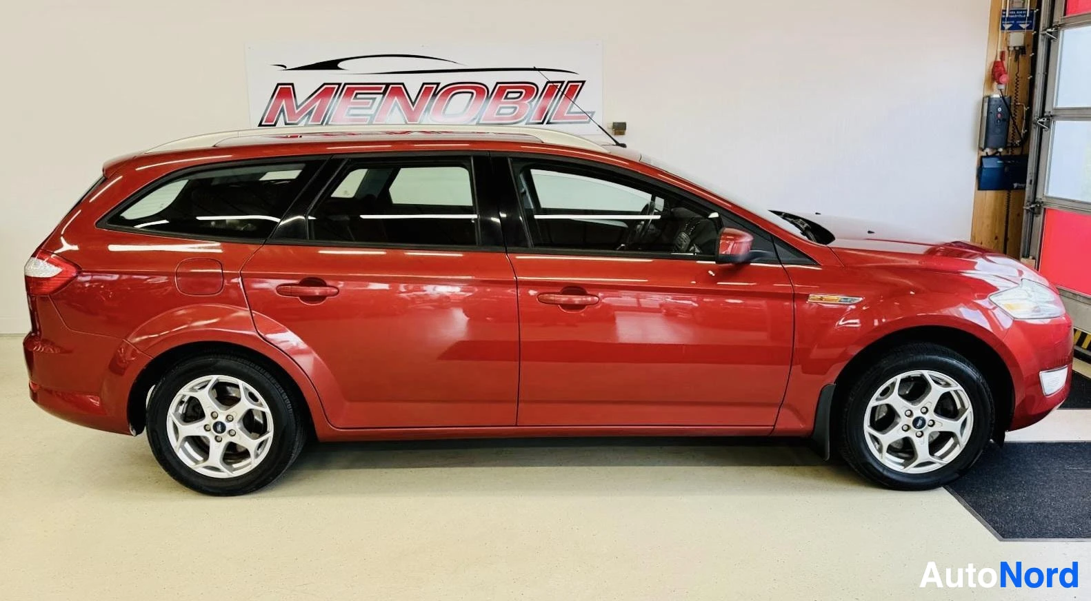 Sivulta: Punainen Ford Mondeo -paketivaunu sivulta kuvattuna, näkyy koko auto profiilinäkymässä, valkoiset alumiinikiekolit, neljä ovea