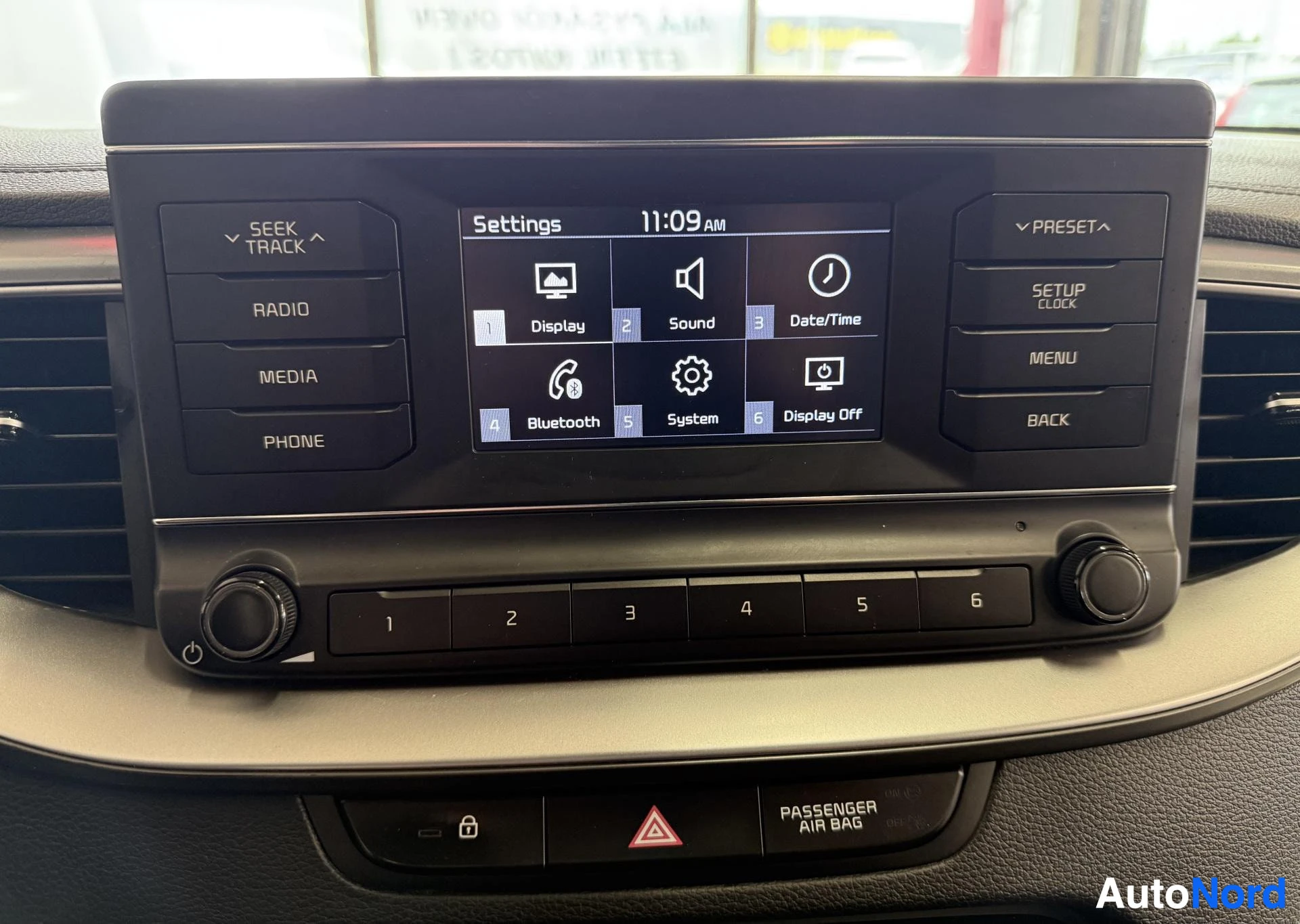 Yksityiskohta: Auton infotainment-järjestelmän näyttö, jossa näkyy asetukset-valikko, jossa on Display-, Sound-, Date/Time-, Bluetooth-, System- ja Display Off -valinnat, sekä