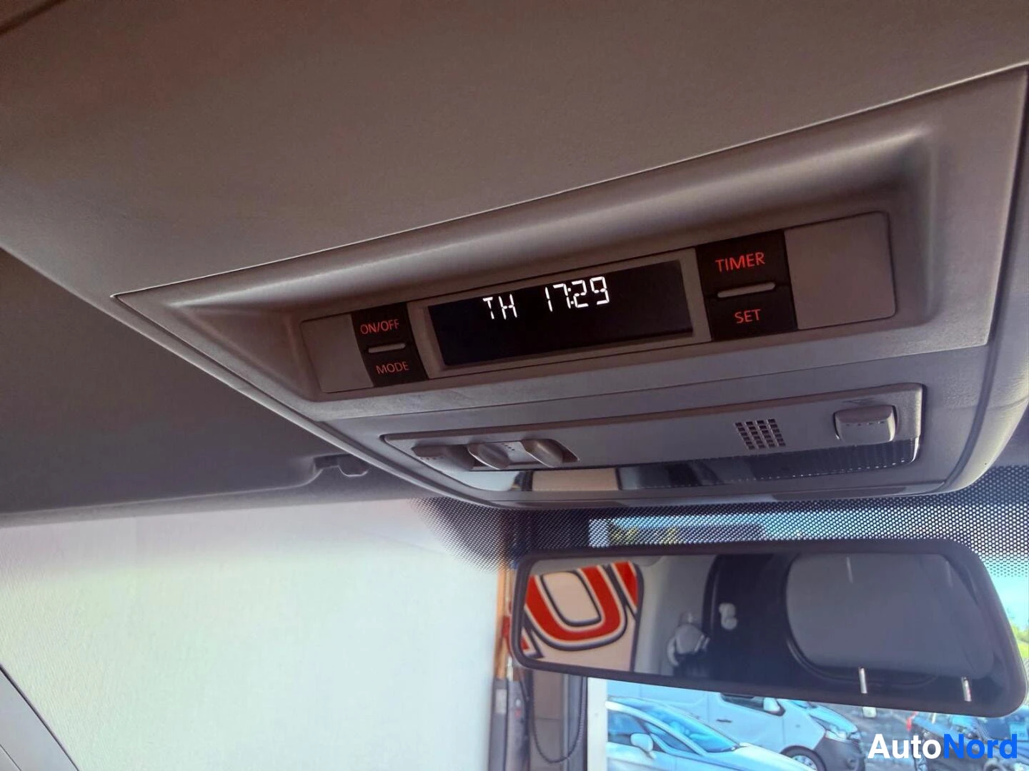 Yksityiskohta: Sisäkaton kellon näyttö ja ilmastoinnin ohjaimet, näyttö näyttää "TH 17:29", painikkeet merkitty ON/OFF, MODE, TIMER ja SET