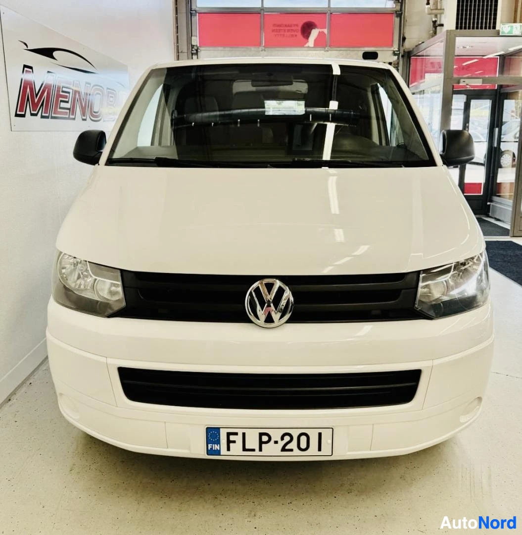 Edestä: Valkoinen Volkswagen-pakettiauto, etunäkymä, rekisteritunnus, VW-merkki näkyvissä grillissä