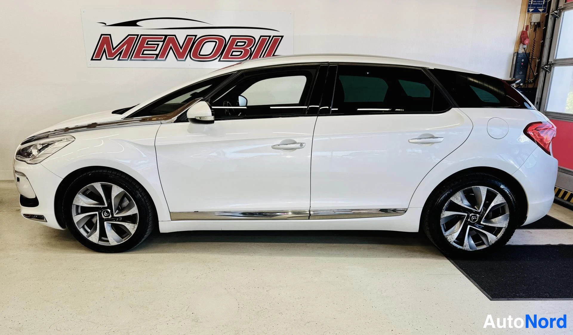 Sivulta: Valkoinen Citroen DS5 sivusta, koko auto näkyvissä, hallissa kuvattu