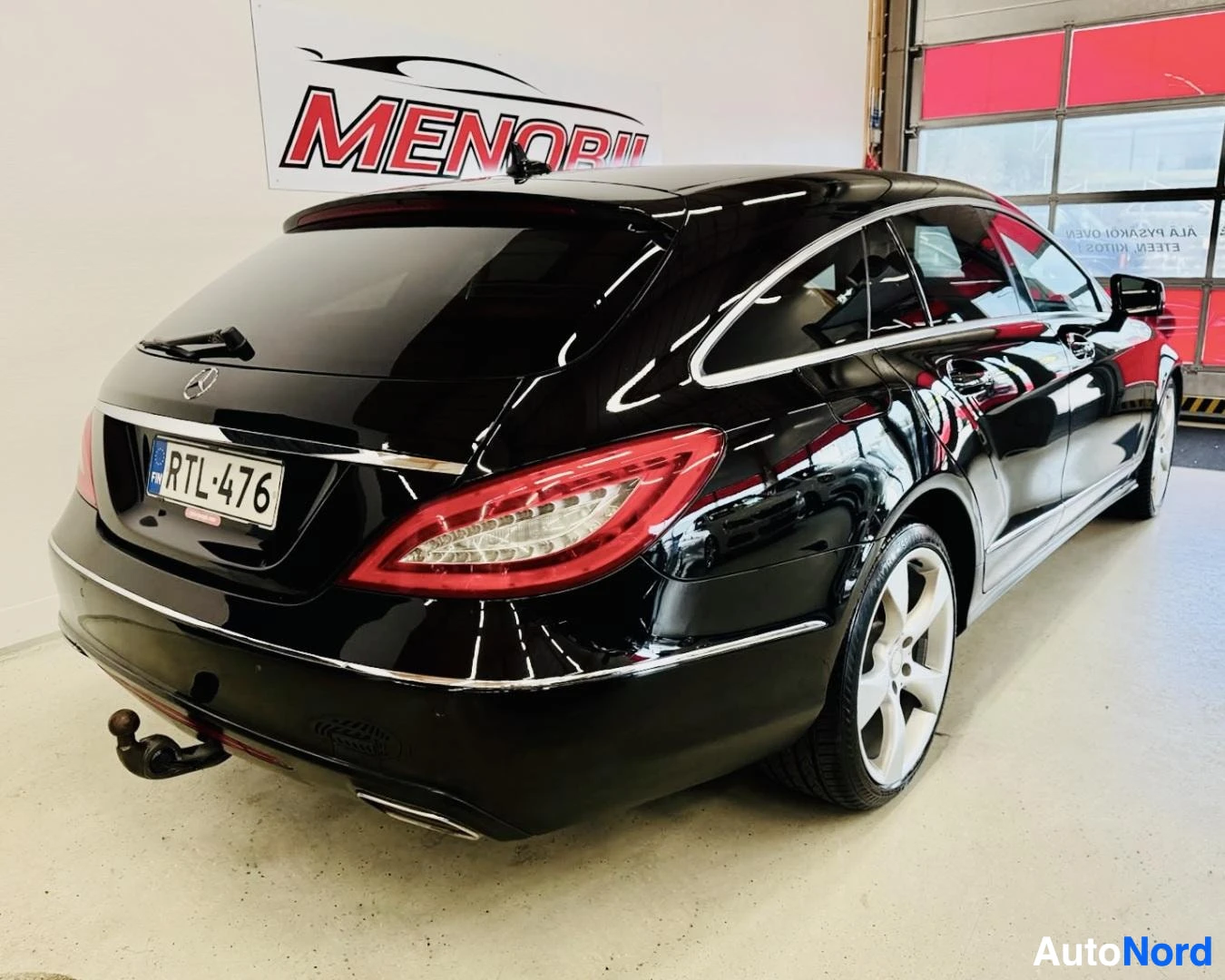 Takaviisto: Musta Mercedes-Benz CLS-sarjan viistoperä sisätiloissa, kuljettajan puoli näkyvillä, takavalon punainen linssi näkyvissä, rekisterinumero näkyvissä taka