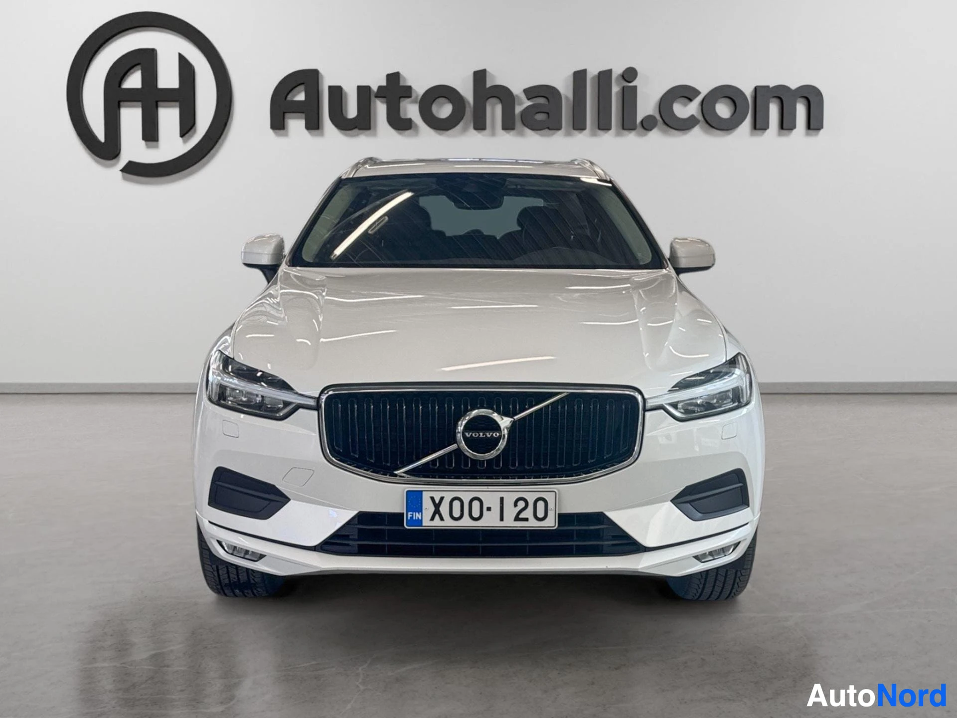 Edestä: Valkoinen Volvo XC60 -maasturi edesta suoraan, rekisterikilpi näkyvissä, grilli ja LED-ajovalot