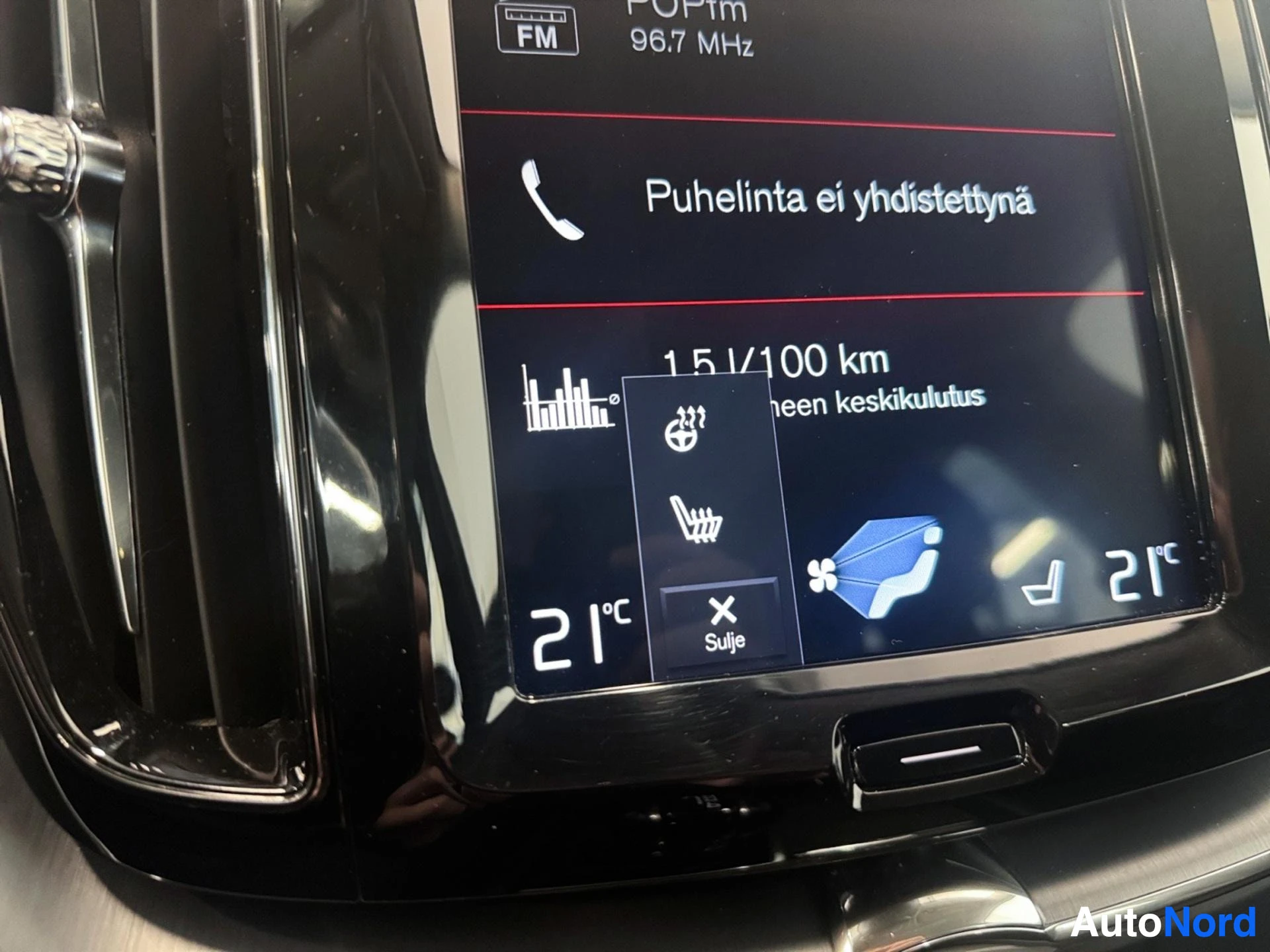 Ohjaamo: Auton keskinäyttö näyttää radiokanavaa 96,7 MHz ja ilmastoinnin kontrolleja, lämpötilan 21°C molemmilla puolilla, istuimen lämmitys kytketty pois päältä.