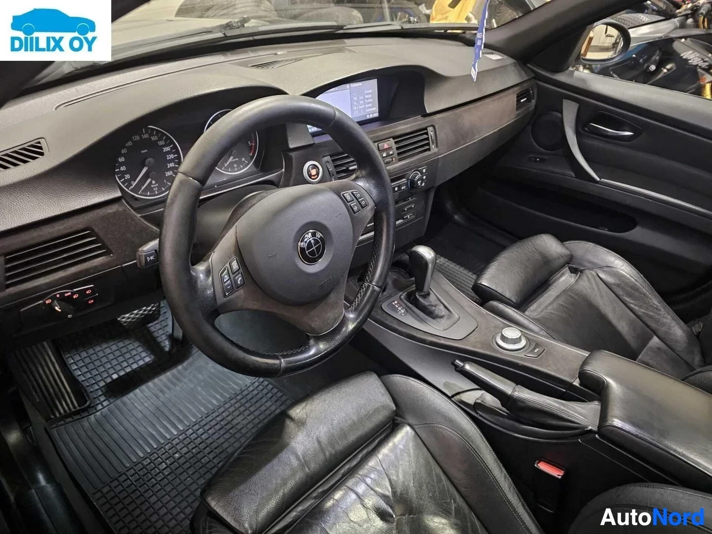 Ohjaamo: Auton ohjaamo, jossa näkyvät ohjauspyörä monitoiminäppäimillä, kojelauta, vaihdekeppi ja iDrive-säädin.