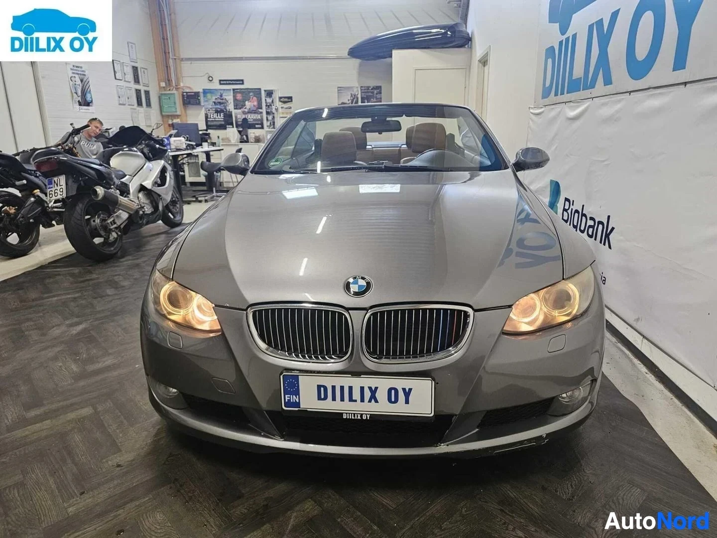 Etuviisto, nokka oikealle: Hopeanvärinen BMW-avoauto etupuolelta oikealle kääntyneenä, kattava auki, sisälle näkyvät istuin-alueet.