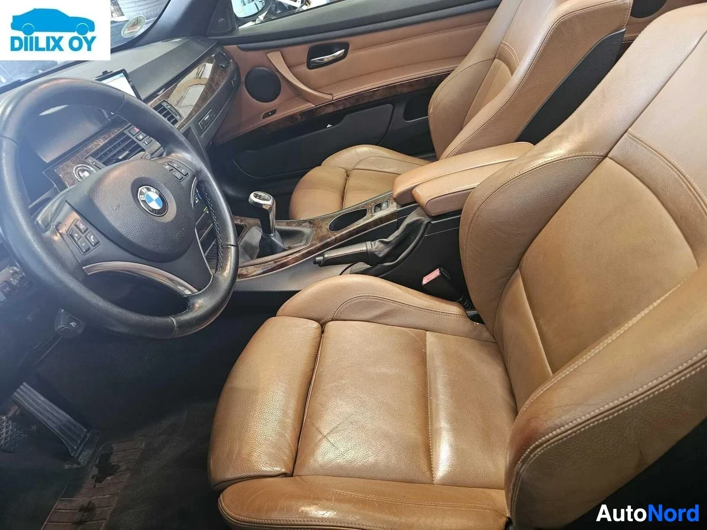 Ohjaamo: Sisäkuva: nahkaverhoillut istuimet, ohjauspyörä BMW-logolla, puu- ja mustanahkainen sisustus, auton etupuoli näkyvissä