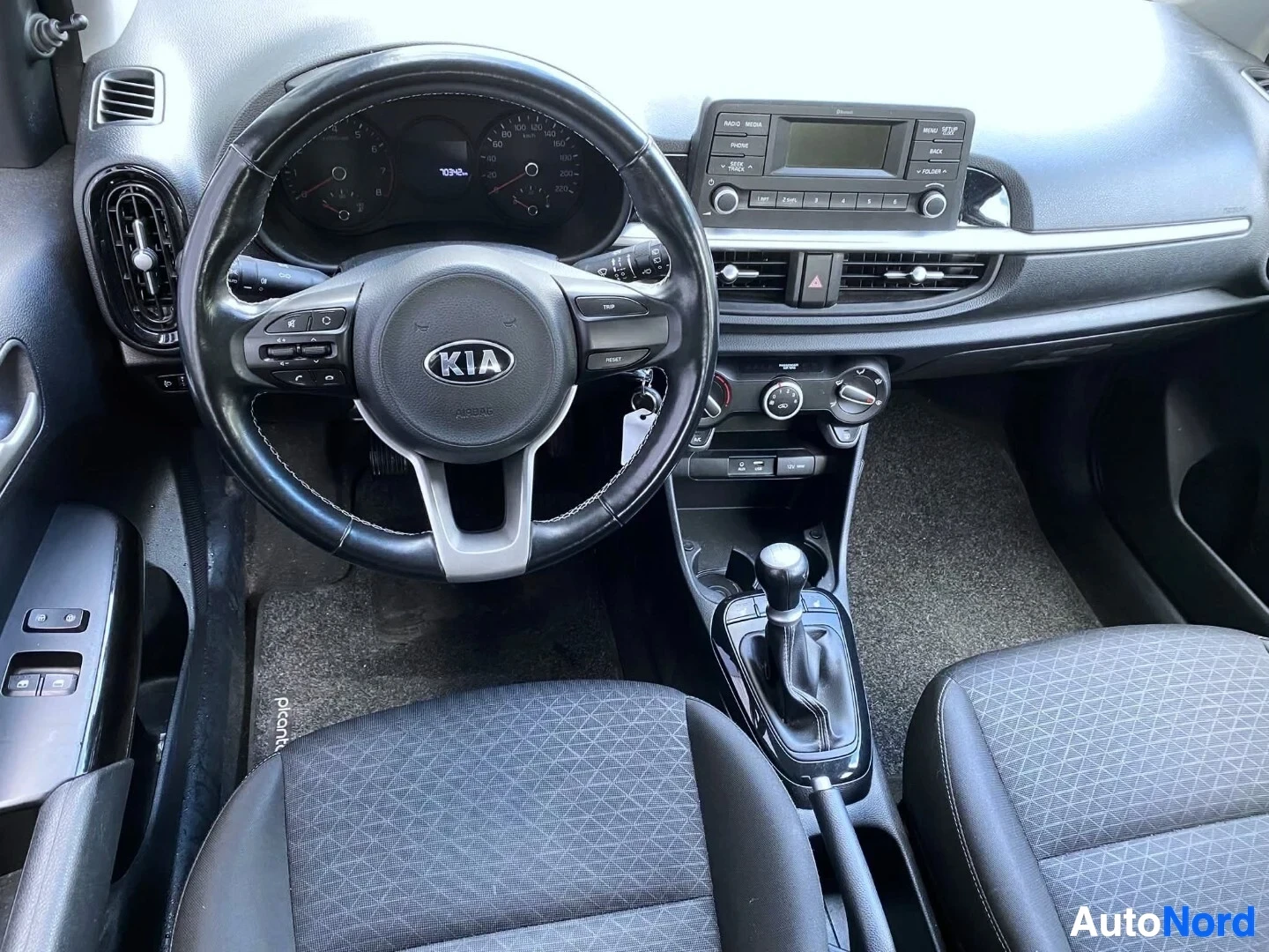 Ohjaamo: Kojelauta auton etuistuimilta kuvattuna, näkyvissä ohjauspyörä, mittaristo, infotainment-järjestelmä ja vaihdekeppi.