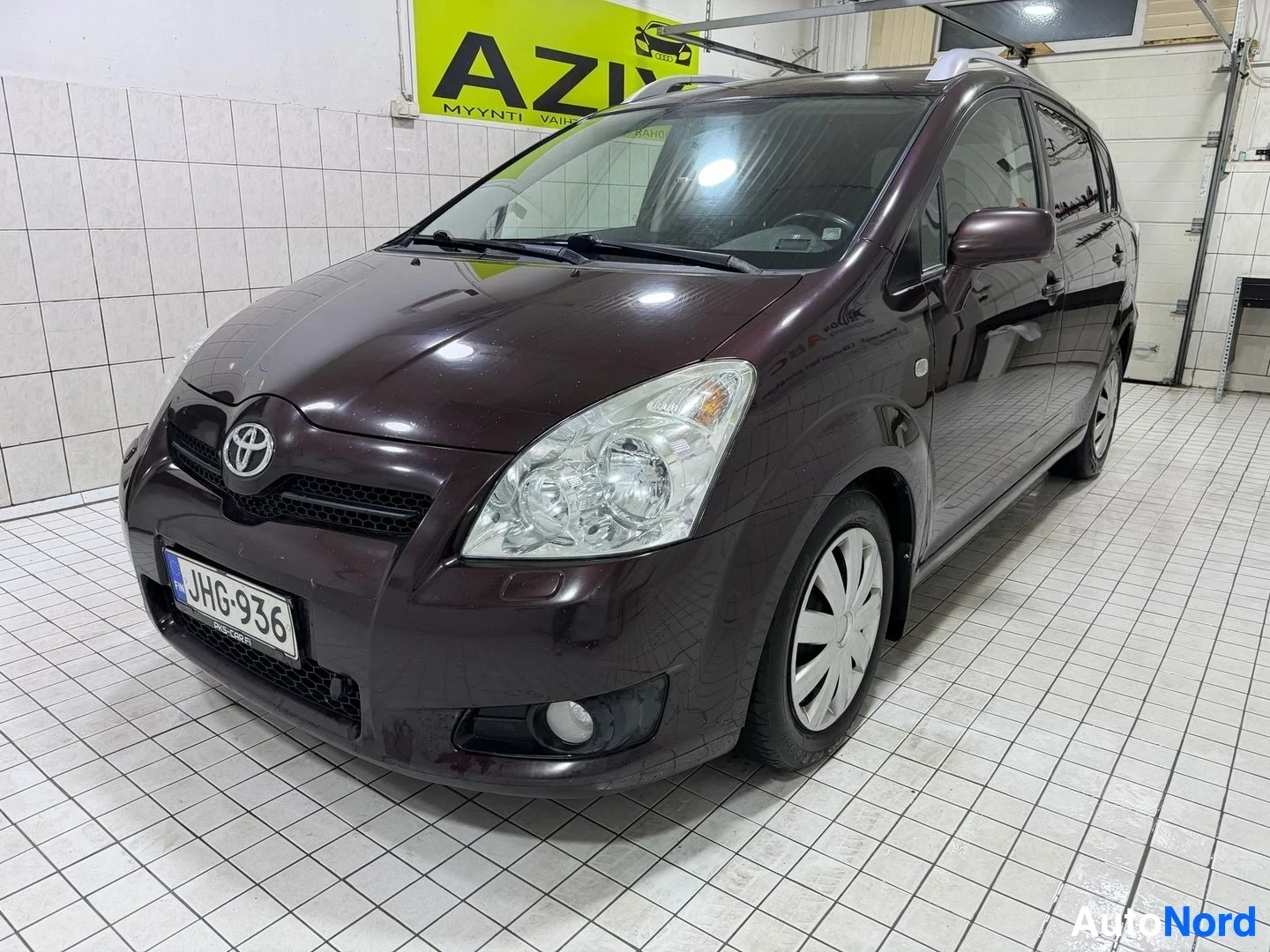 Etuviisto, nokka oikealle: Tummanruskea Toyota -tila-auto vasemmalla kuljettajan puolella olevan kuvan etuviistosta, kylmävaraston sisäpuolella
