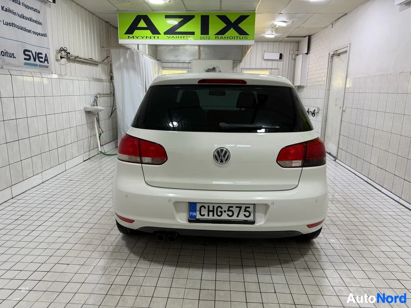Takaa: Valkoinen Volkswagen Golf, takakuva hallissa, punaisia takavalojakilillä