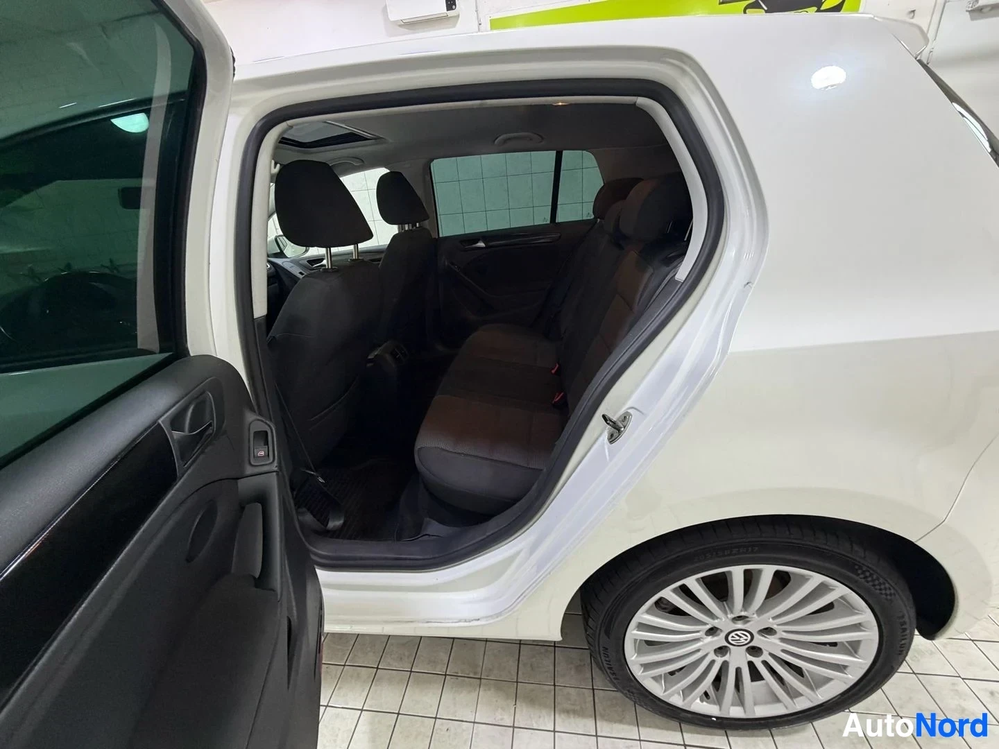 Takaistuimet: Valkoinen Volkswagen Golf takaoven avoimena näkyvillä takaistuimilla ja hopeanvärisillä loukkarinrengailla, mustuista takaistuimista näkyy osa.