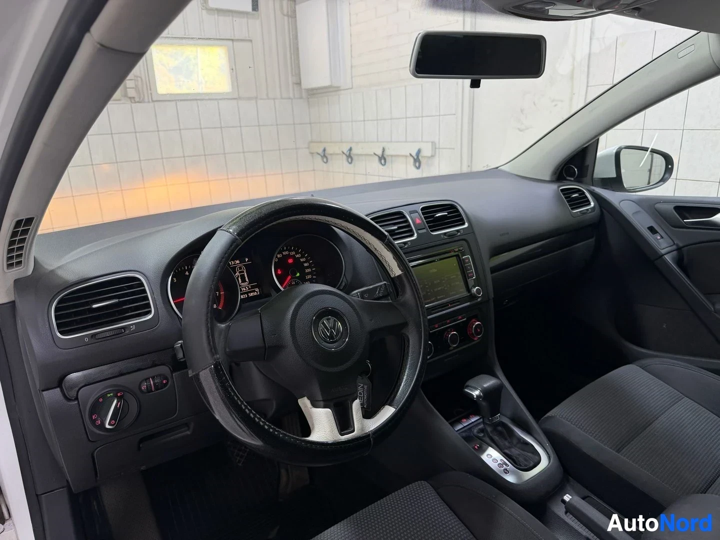 Ohjaamo: Volkswagen Golfin ratti ja kojelauta kauempaa, punainen mittarineulan väri, digitaalinen näyttö keskeisesti, mustat sisäosat.