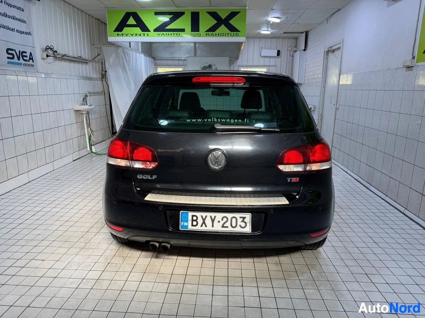 Takaa: Volkswagen Golf takaa, musta auto, rekisterikilpi, punaisten takavalojen näkyvissä, sisätiloissa