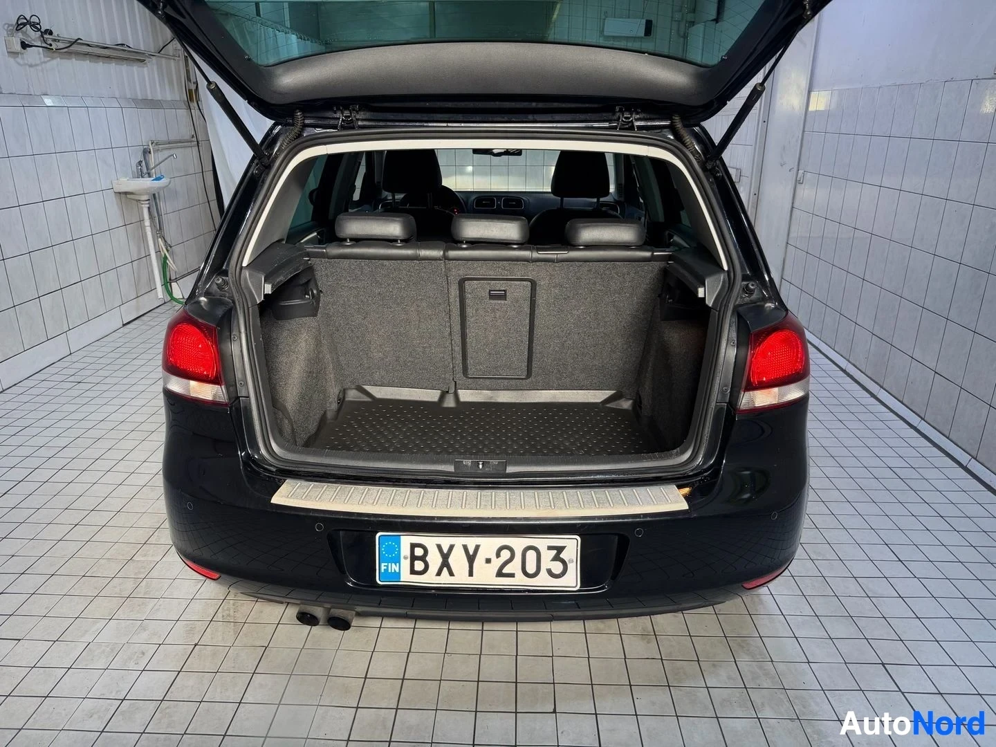 Tavaratila: Musta Volkswagen Golf-tyyppinen auto, takaluukku auki, näkyy lastauatila ja rekisteritunnus