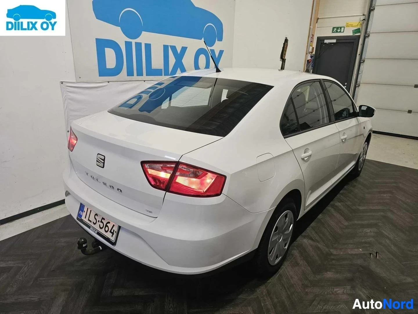 Takaviisto: Valkoinen Seat Toledo seisoo autotallissa takaosastaan näkyvissä. Auton takaosassa näkyy teksti TOLEDO ja rekisterikilvessä