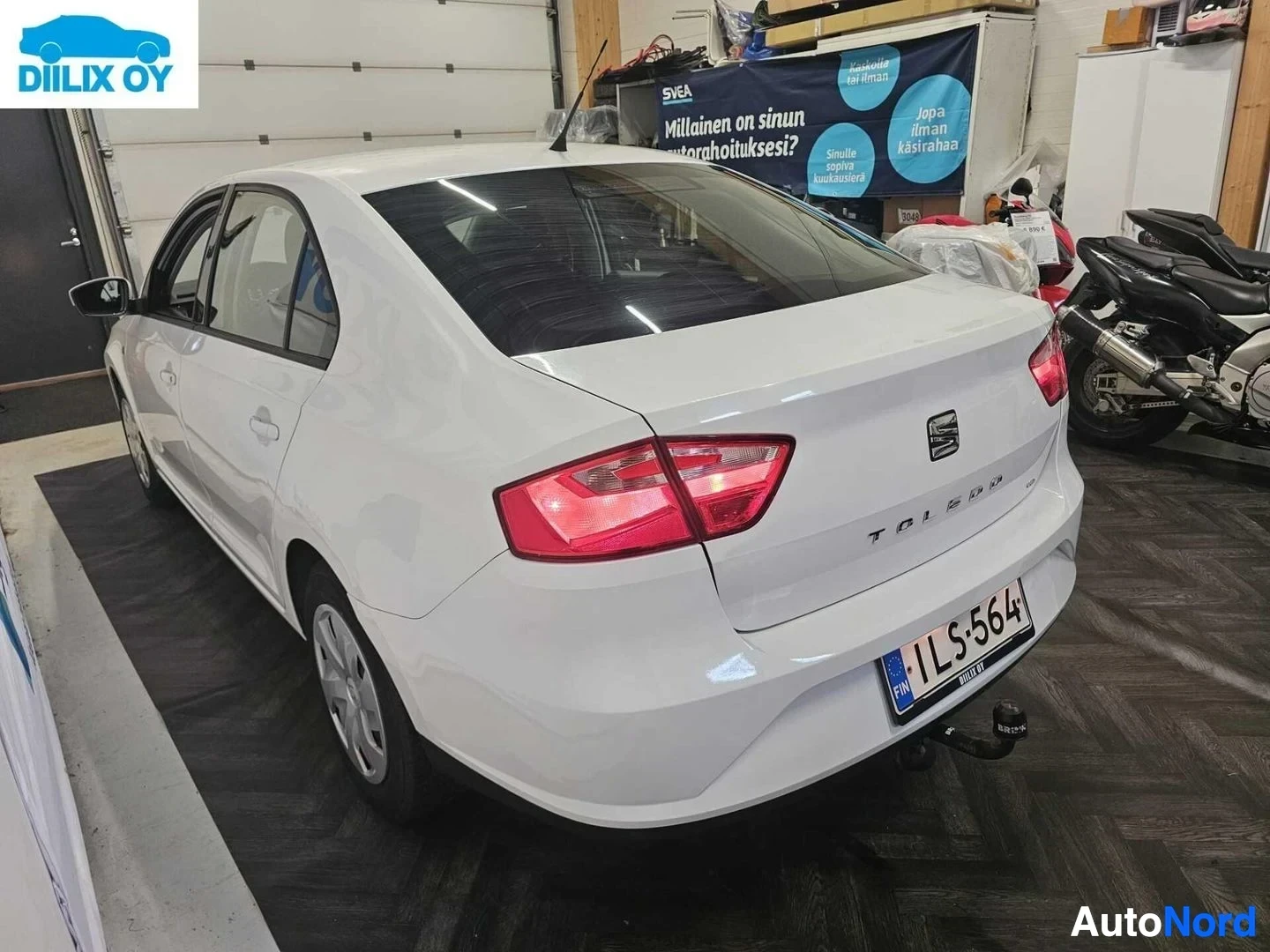 Takaa: Valkoinen Seat Toledo seisoo autotallissa takaosastaan näkyvissä, hieman vasemmalle käännettynä. Auton takaosassa näkyy teksti TOLEDO ja rekisterikilvessä 1LS-5