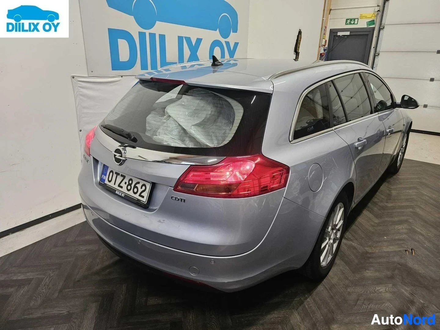 Takaviisto: Opel Insignia -farmarin takaosa ja oikea sivu, takaluukku auki, rekisterikyltti näkyvillä, takavalot punaiset, käyttövaruste-merkinnöt sivulla