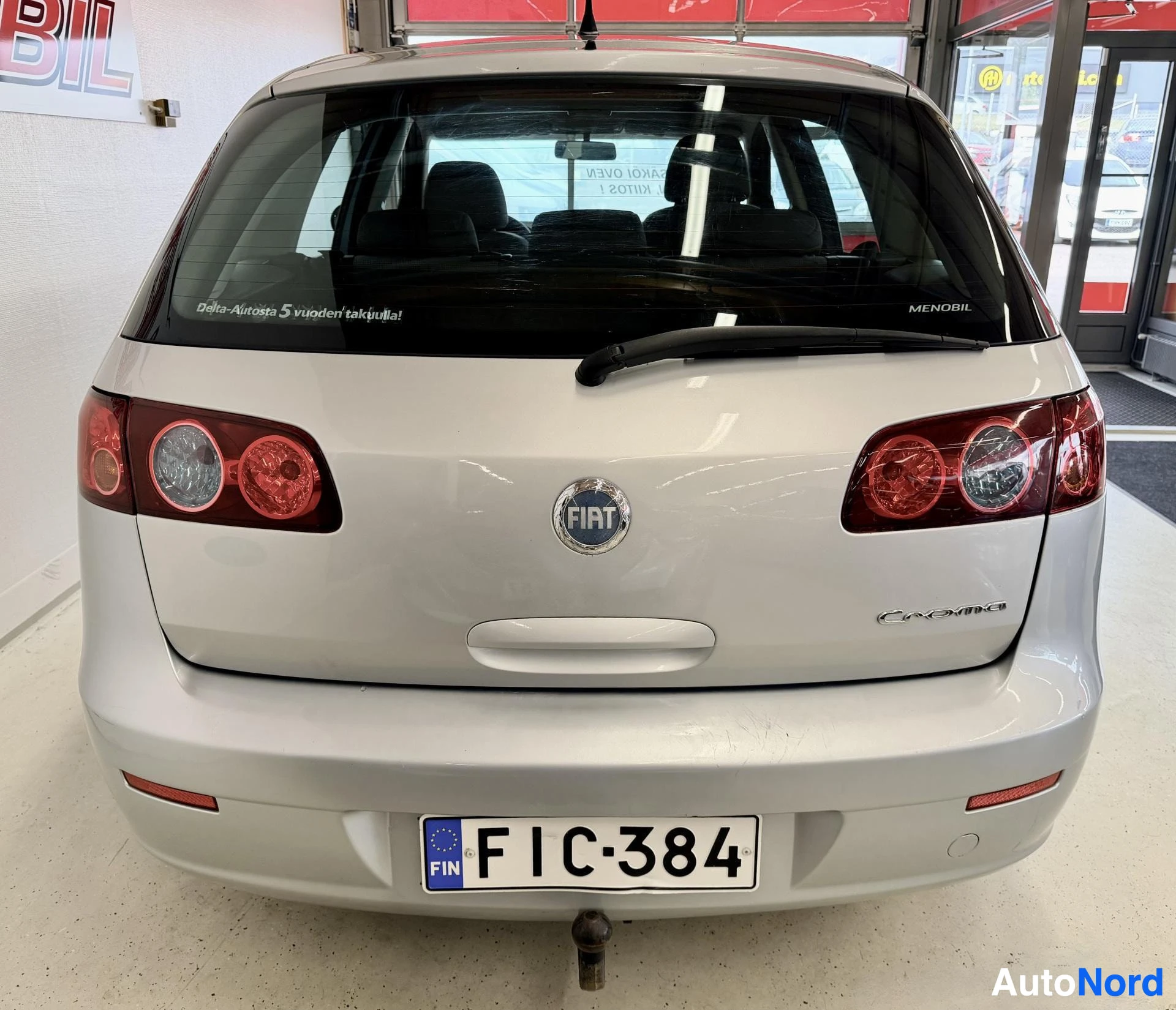 Takaa: Valkoinen Fiat Croma takaa kuvattuna sisätiloissa. Näkyy rekisterikyltti, Fiat-merkki, takavalot ja CROMA-teksti