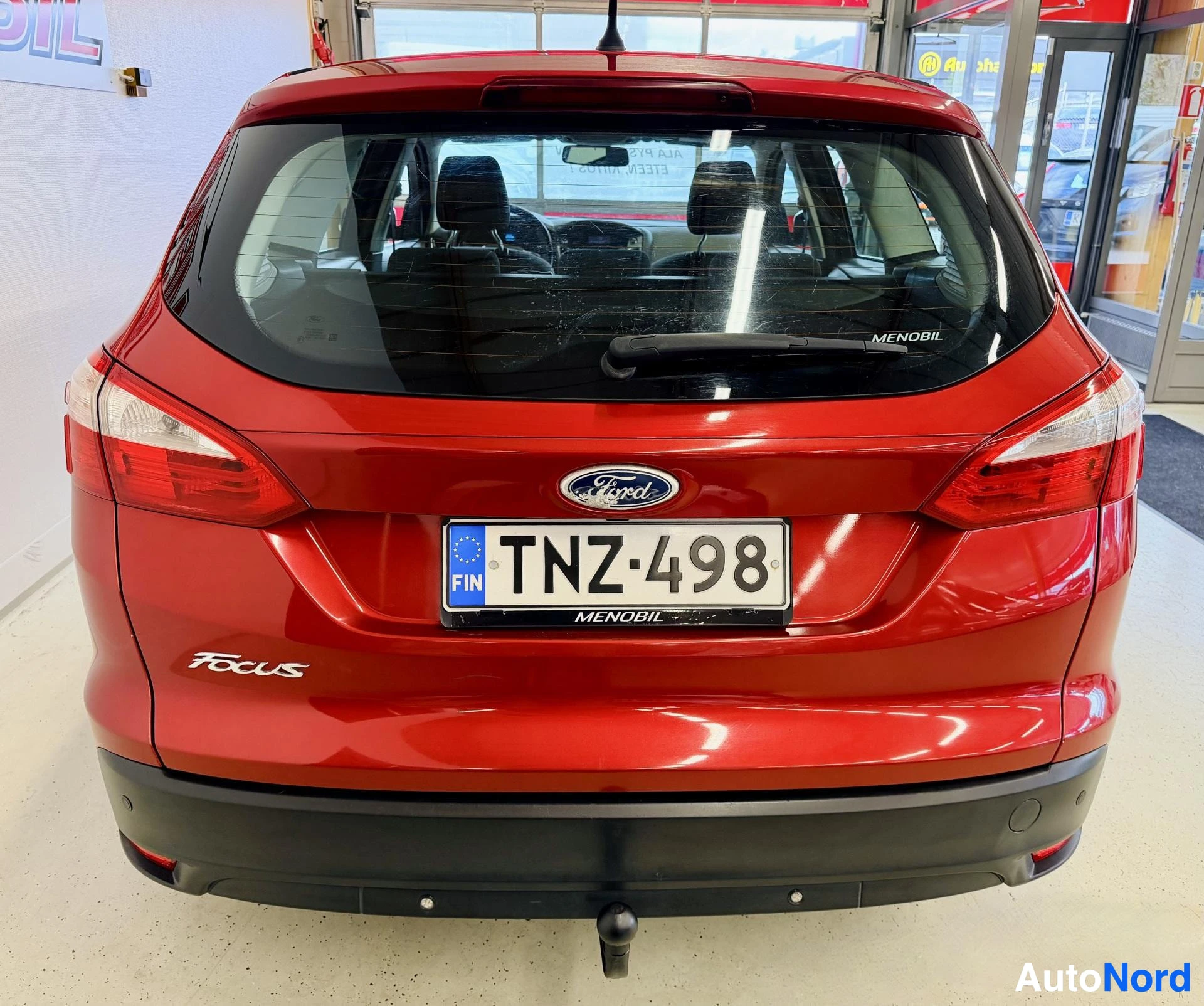 Takaa: Punainen Ford Focus -farmarin takaosa, rekisterikylpi (FIN), Ford-tunnus, FOCUS-teksti takakyllen alalaidassa, vetosilmä