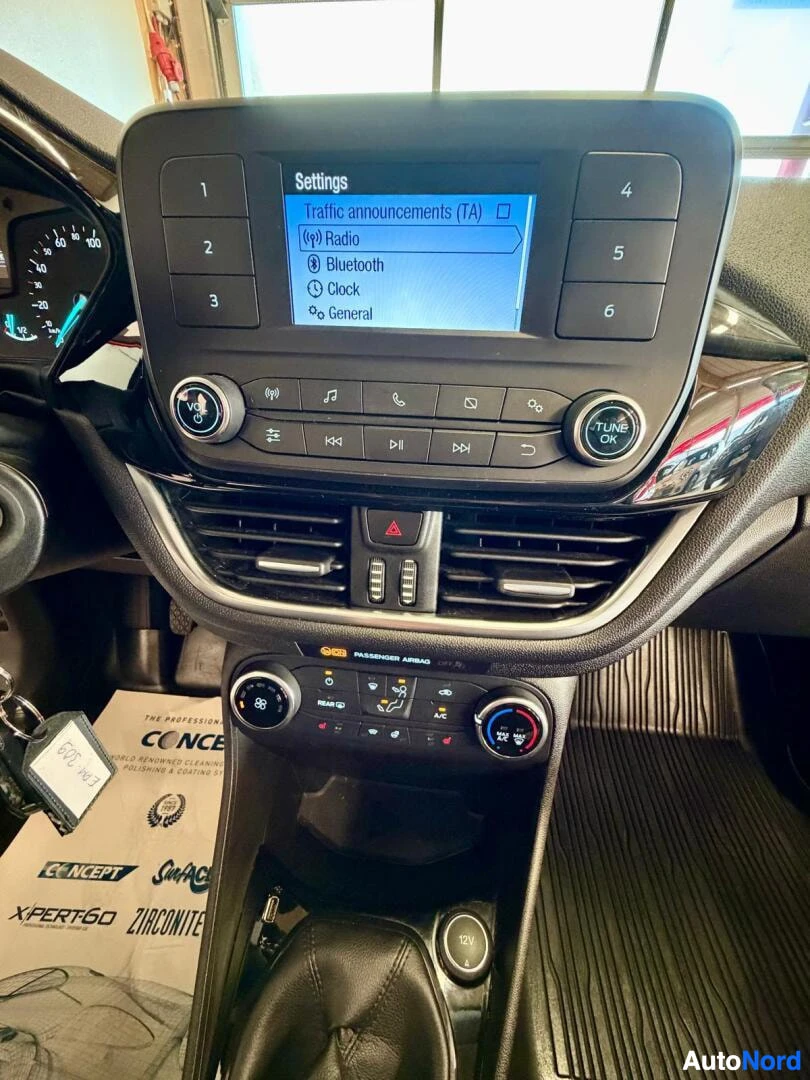 Yksityiskohta: Kosketusnäytön asetusvalikko näkyy sinisellä näytöllä, jossa näkyy Traffic announcements (TA), Radio, Bluetooth, Clock ja General -vaihtoehdot