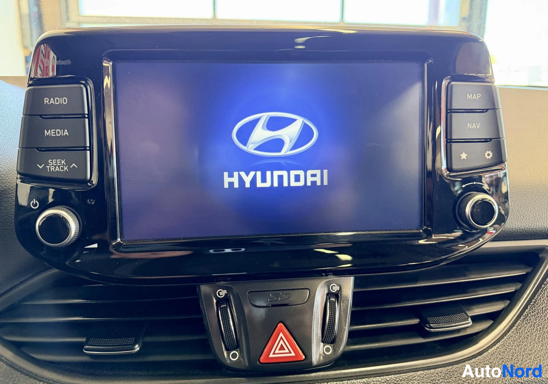 Ohjaamo: Hyundai-merkin logo ja teksti valkoisella kirjoituksella sinisellä keskinäytön pohjalla