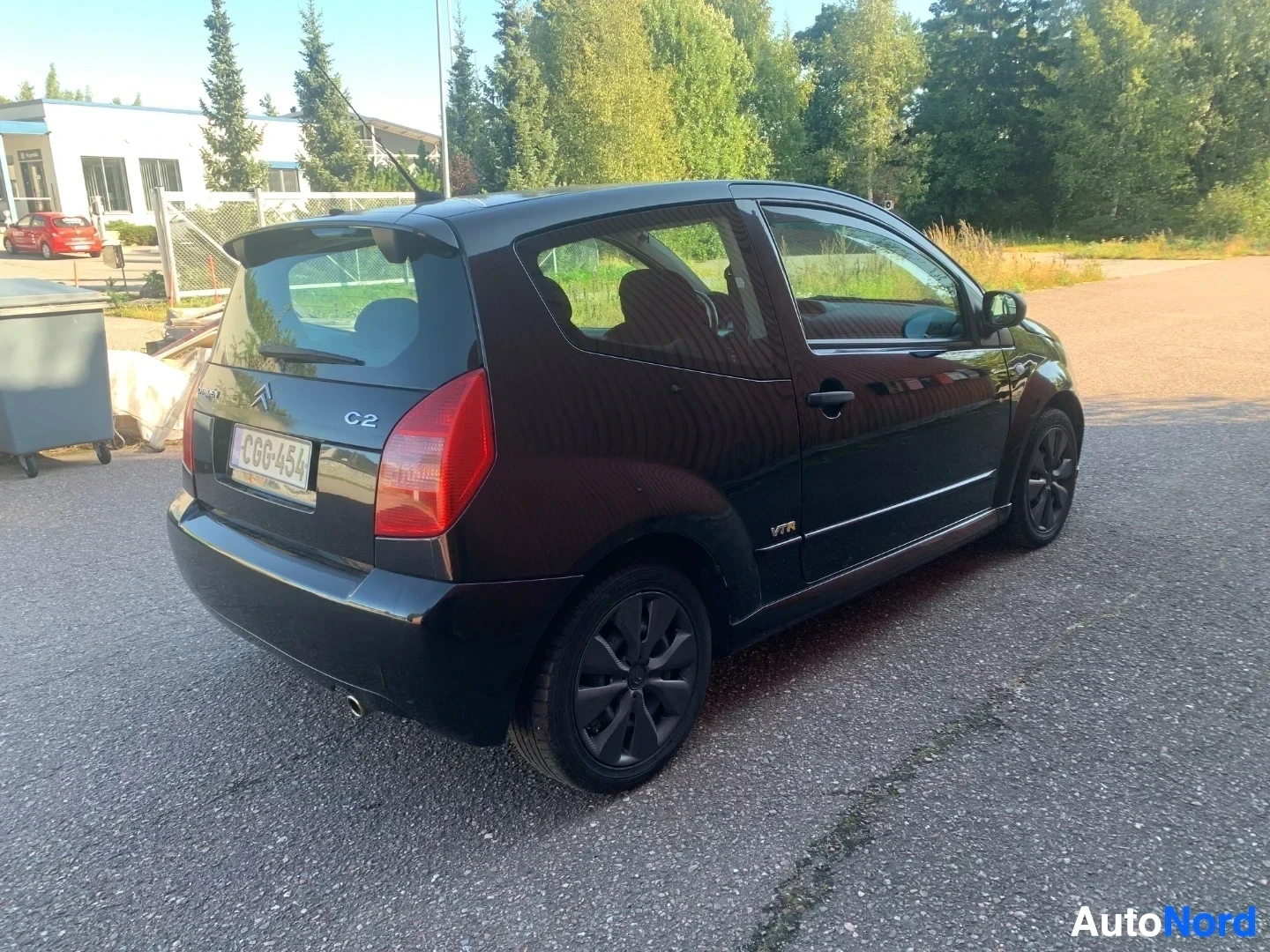 Takaviisto: Musta Citroën C2 takapuoli avoimella ovenä näyttäen sisustaa, rekisteritunnus CG6454, pysäköity betonille varaston pihalle
