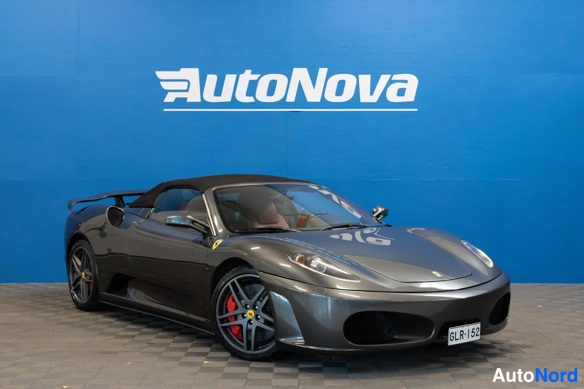 Etuviisto, nokka oikealle: Ferrari F430 Spider harmaa urheiluauto, musta kangaskatto kiinni, etuoikealta.