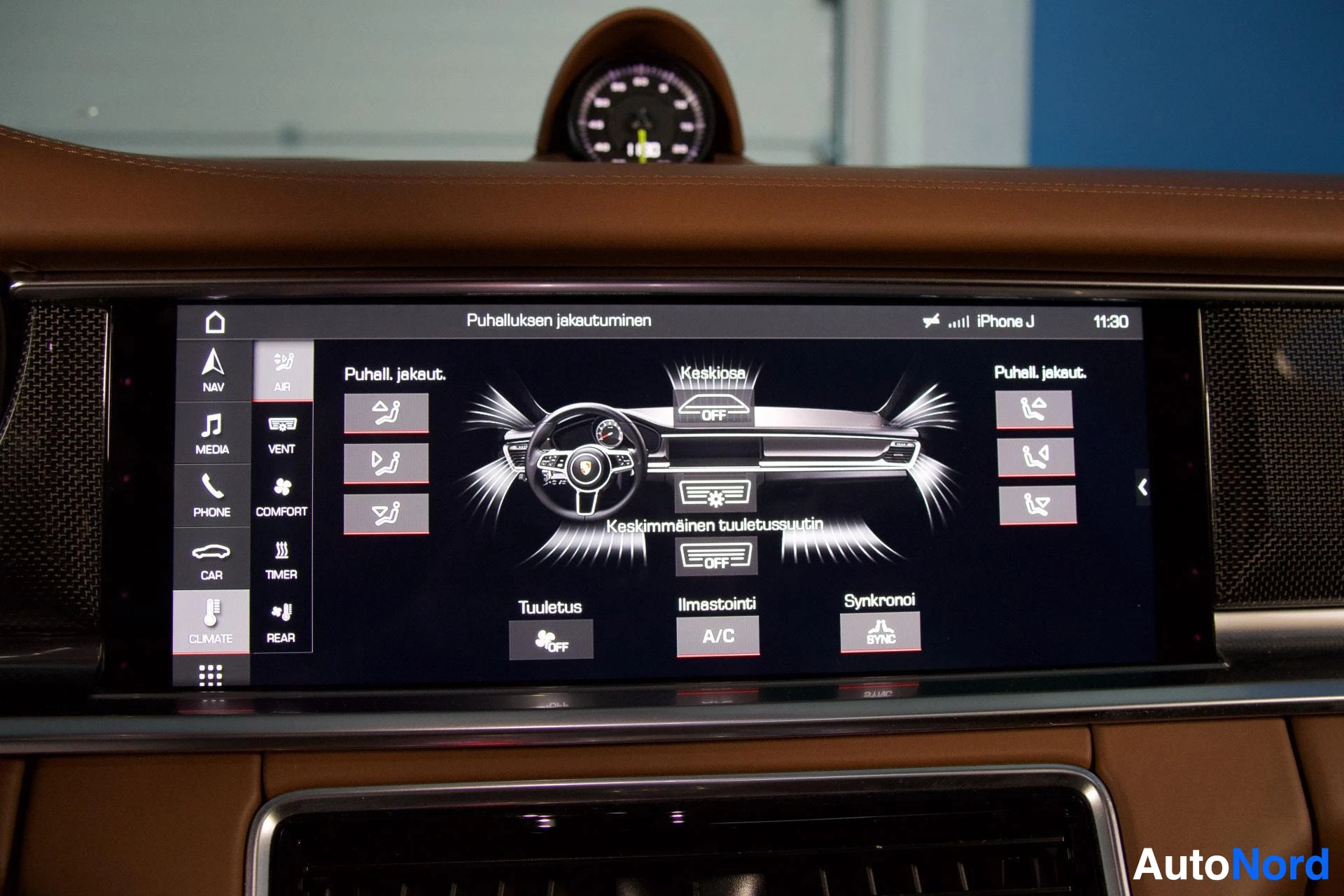 Ohjaamo: Lähikuva auton kojelaudan infotainment-näytöstä, jossa näkyy ilmastoinnin ohjauspaneeli suomen kielellä. Näytössä on "Puhalluksen jakautuminen" ja useita ilmast