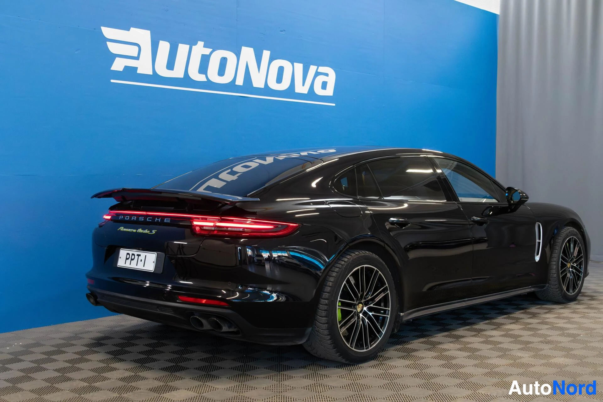 Takaviisto: Musta auto on pysäköity niin, että sen oikea kylki ja takaosa näkyvät diagonaalisesti edestäpäin. Takaluukussa on rekisterikilpi "", Porsche-merkki ja Panamera
