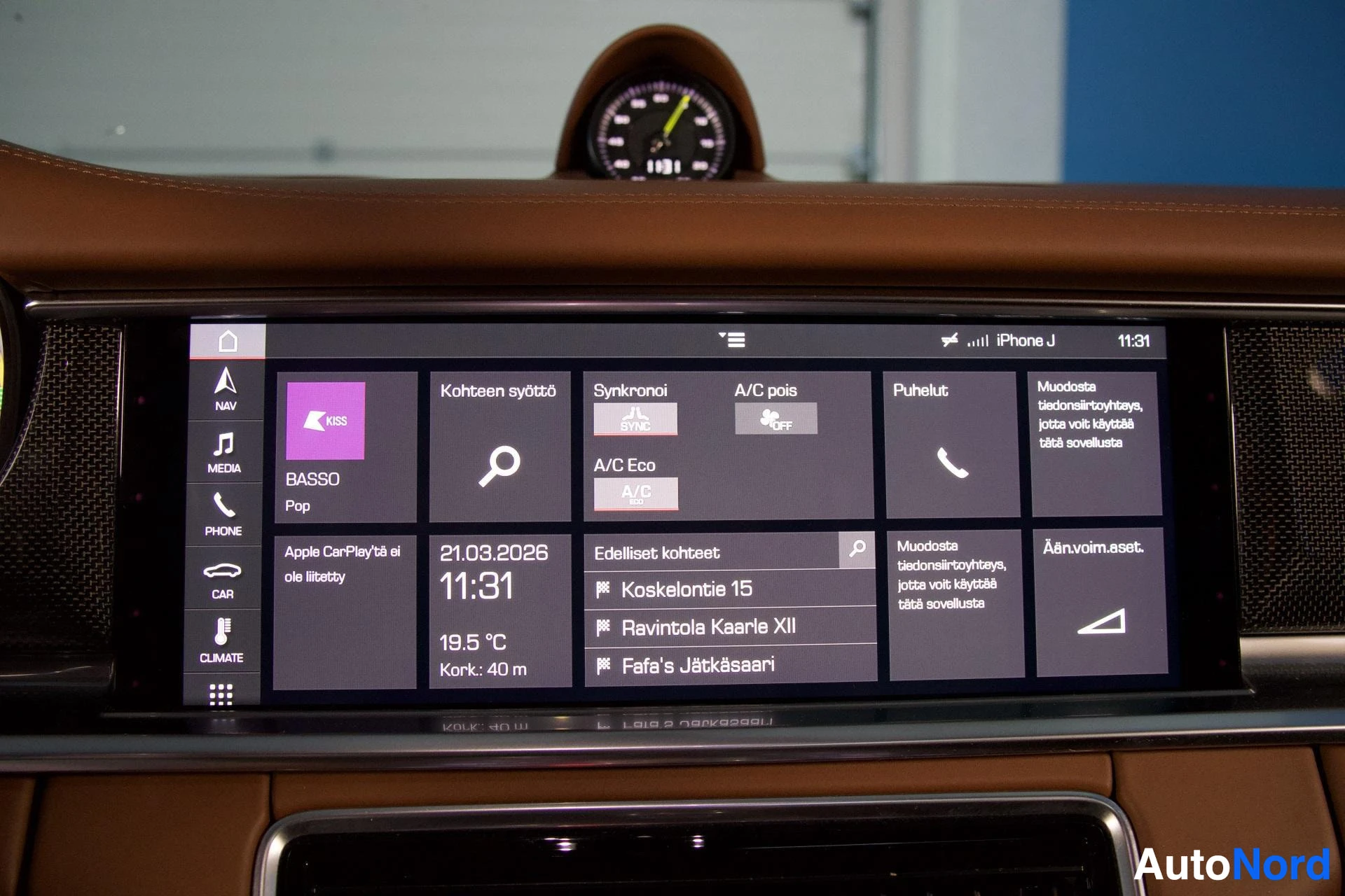 Ohjaamo: Lähikuva auton kojelaudan infotainment-näytöstä, jossa näkyy käyttöliittymä useine toimintoineen, kuten navigointi, puhelin ja media. Näytöllä on useita suomenk