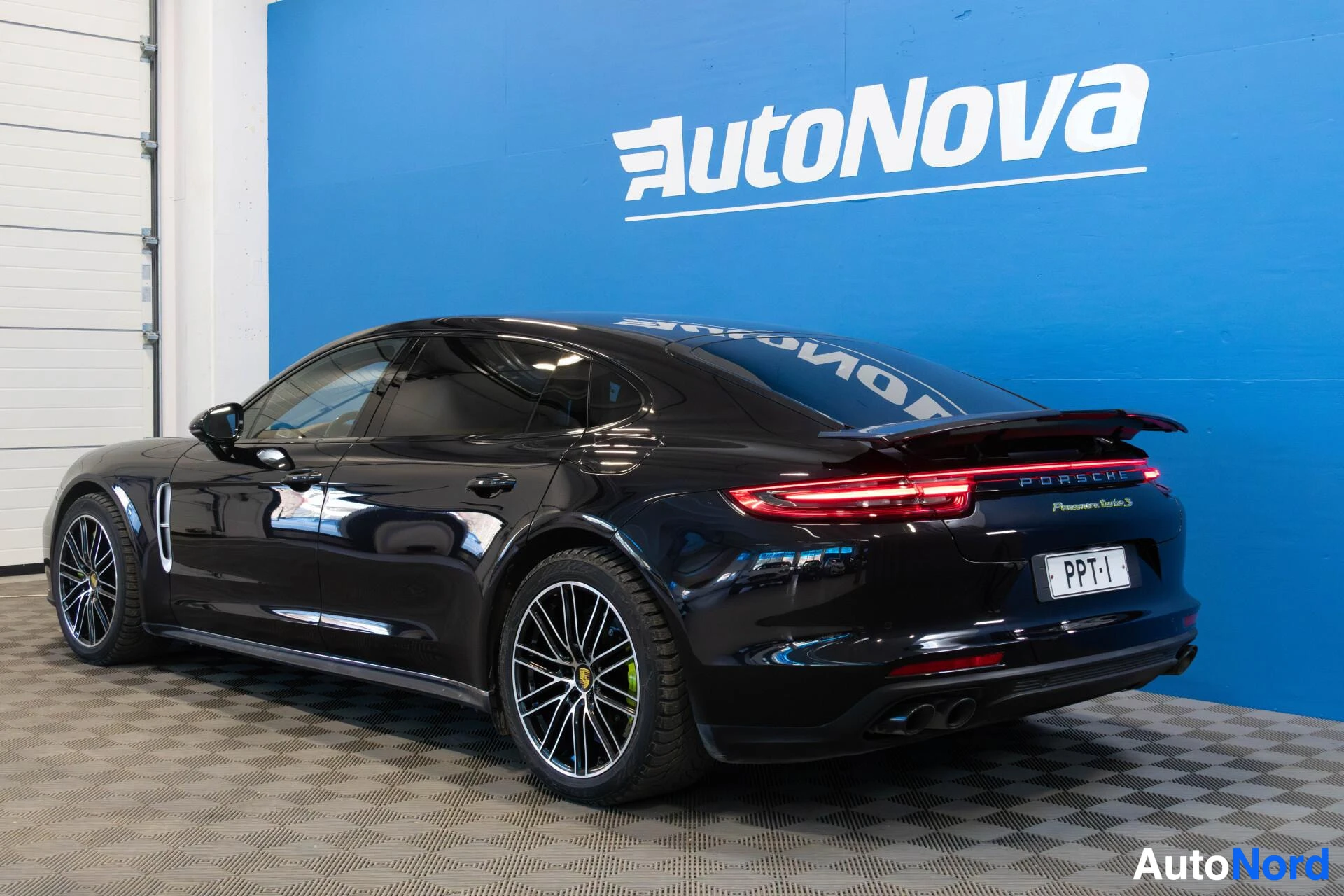 Takaviisto: Musta auto on pysäköity niin, että sen oikea kylki ja takaosa näkyvät diagonaalisesti edestäpäin. Takaluukussa on rekisterikilpi "", Porsche-merkki ja Panamera
