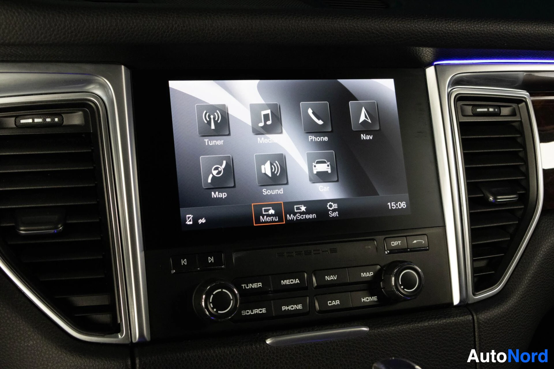 Yksityiskohta: Auton infotainment-näyttö, jossa näkyy päävalikko. Valikossa on kuvakkeita ja tekstejä kuten "Tuner", "Media", "Phone", "Nav", "Map", "Sound" ja "Car". Alareuna