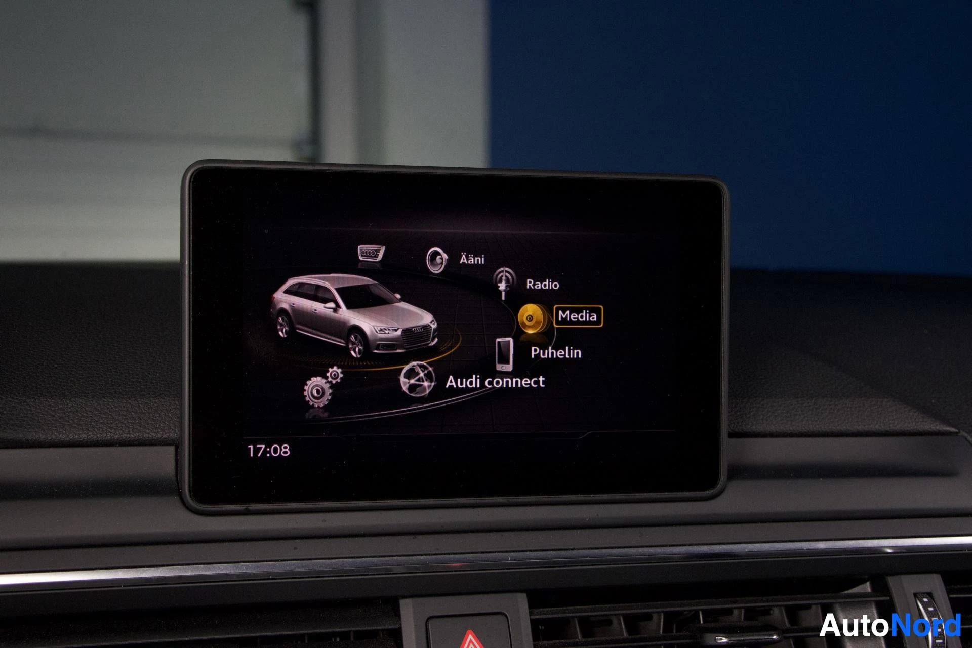 Yksityiskohta: Autoon asennetun näytön Audi connect -päävalikko, jossa näkyvät Radio, Media ja Puhelin-vaihtoehdot sekä Audi-logon ja auton kuva