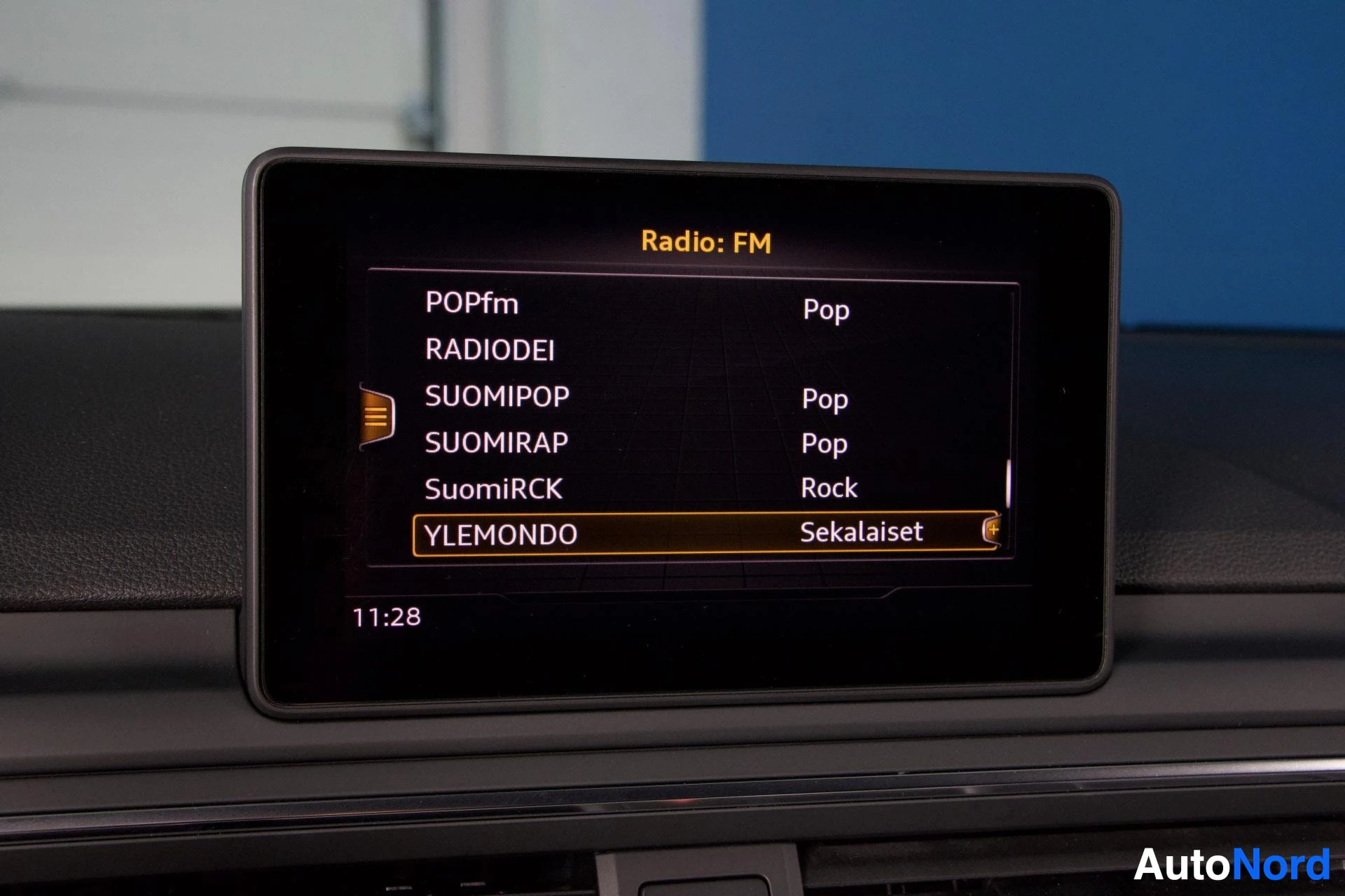 Yksityiskohta: Audin multimedia-näyttö, jossa FM-radiokanavien valikkoa eri radioasemilla kuten YLEMONDO