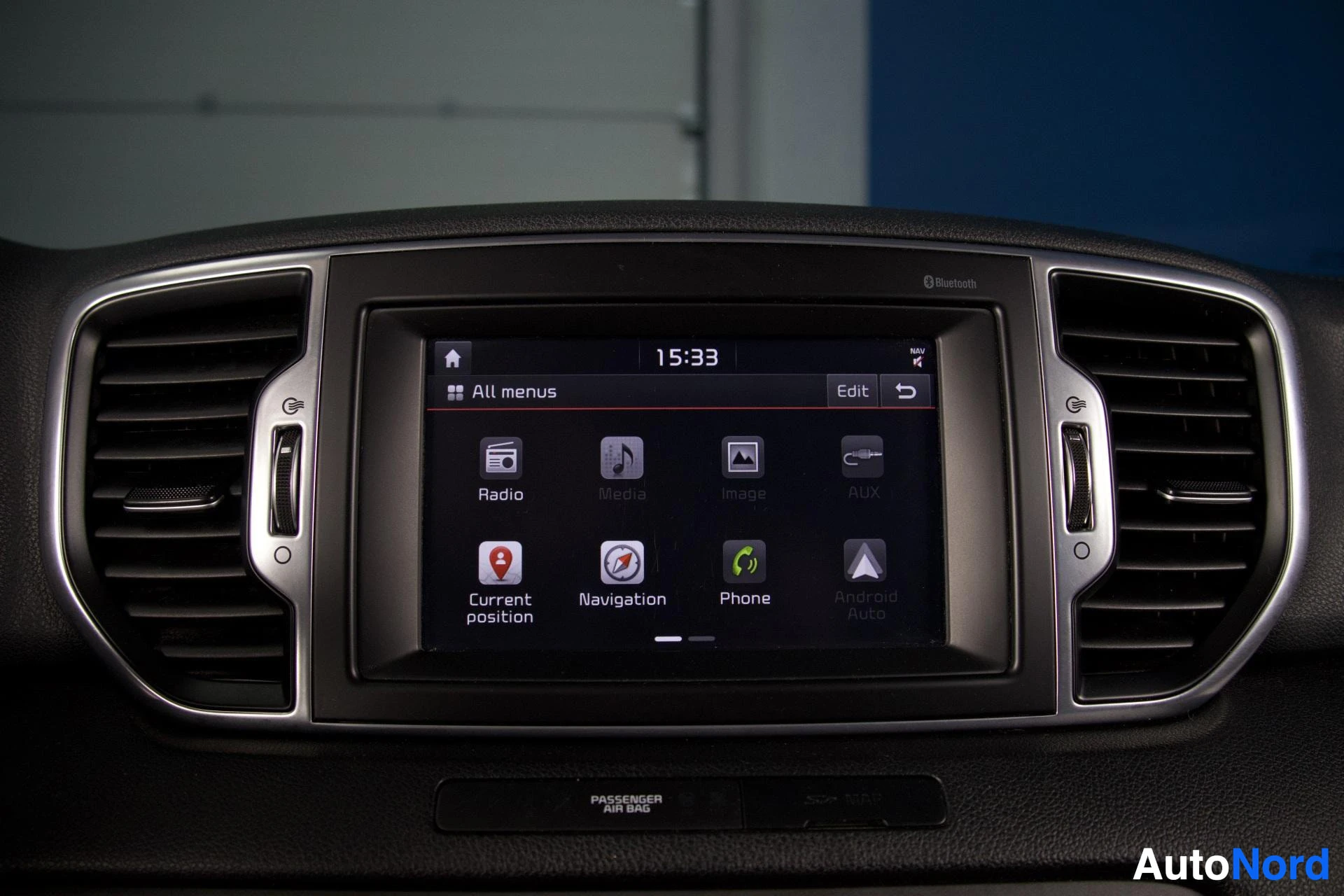 Yksityiskohta: Lähikuva keskikonsolin näytöstä, jossa näkyy päävalikko kuvakkeilla "Radio", "Media", "Image", "Aux", "Current position", "Navigation", "Phone" ja "Android Auto
