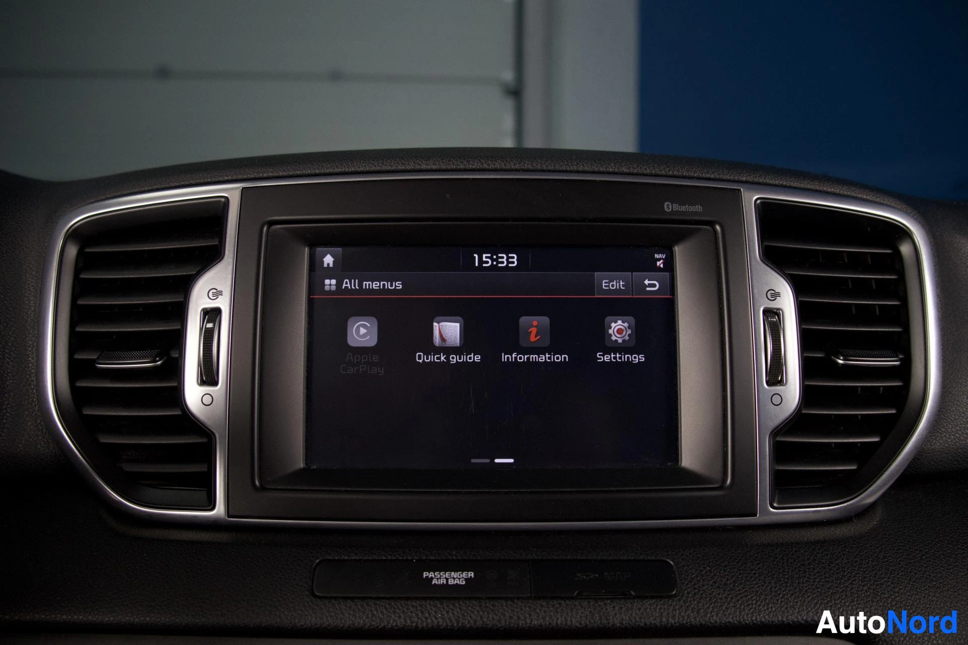 Yksityiskohta: Lähikuva auton kojelaudan tietoviihdejärjestelmän näytöstä, jossa näkyy päävalikko kuvakkeilla 'Apple CarPlay', 'Quick guide', 'Information' ja 'Settings'. Näyt