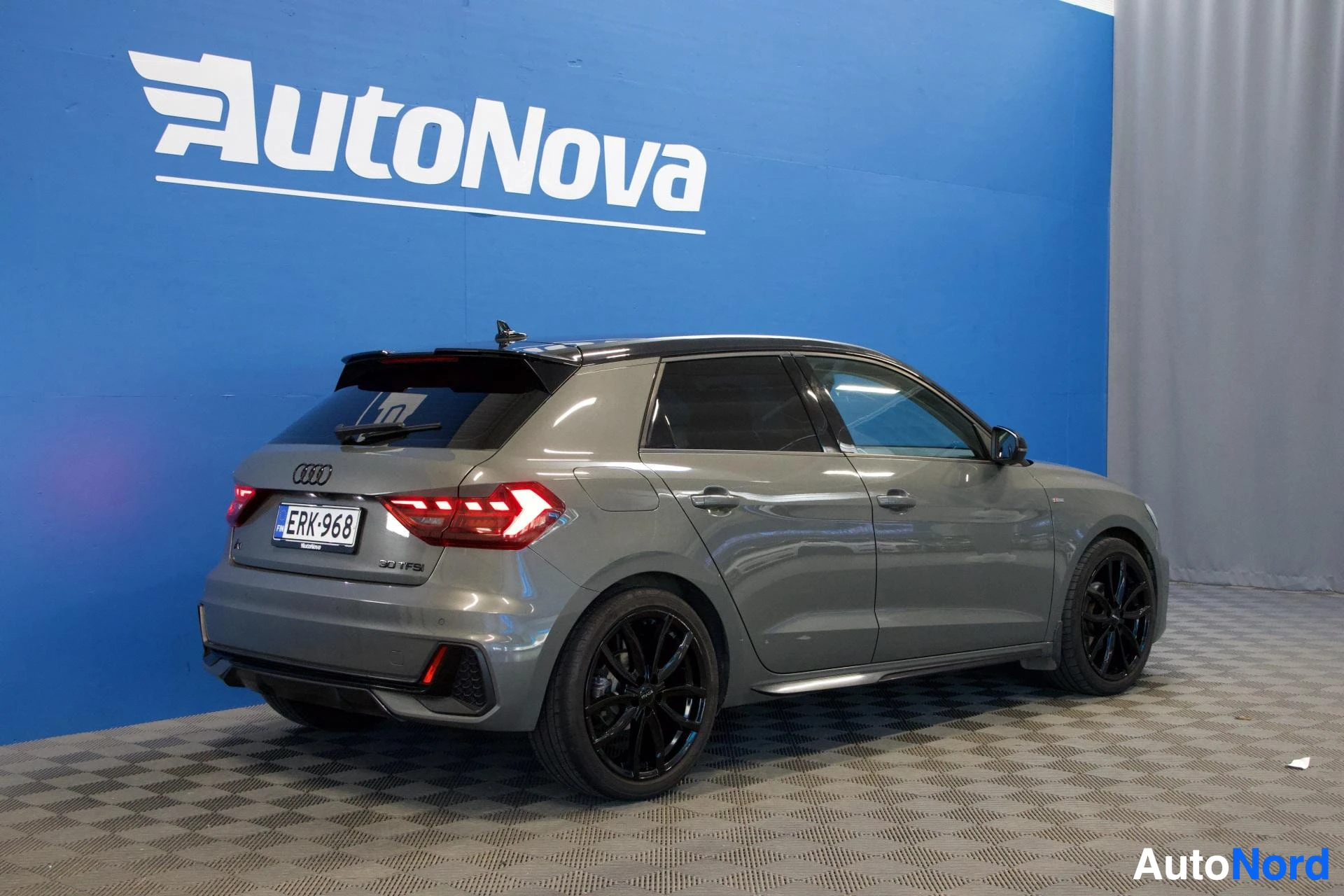 Takaviisto: Audi A1 Sportback takaa kolmelta kulmalta, rekisterinumero näkyy, harmaa väri, tummat vanteet