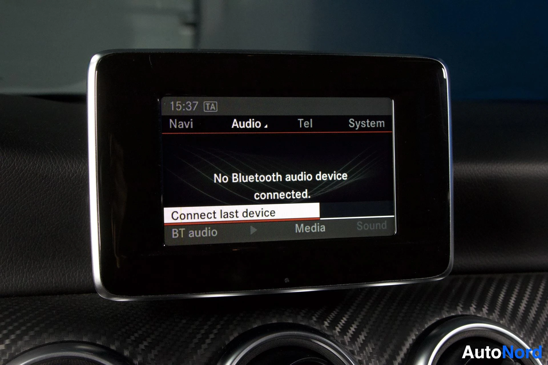 Yksityiskohta: Lähikuva auton kojelaudan infotainment-näytöstä, jonka Audio-valikossa lukee 'No Bluetooth audio device connected.' ja vaihtoehto 'Connect last device'. Valikko