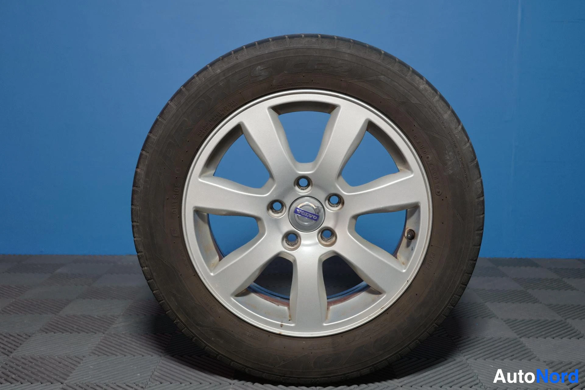 Yksityiskohta: Valkoinen vanne ja kesärenkaat, lähikuva. Vanteessa näkyy Volvo-logo keskiosassa.